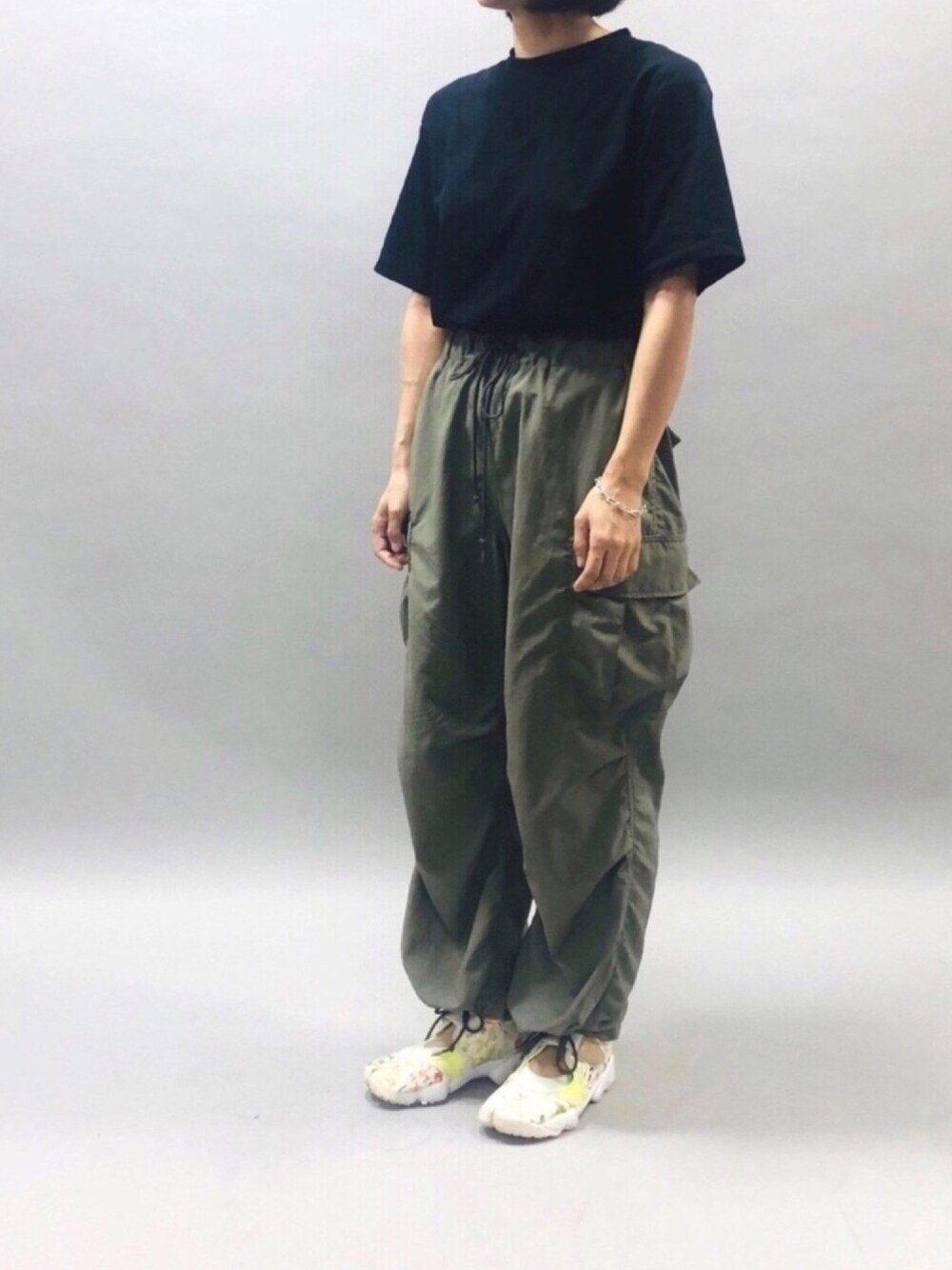 グリーン系のカーゴパンツ、ブラック系のTシャツ/カットソー、ホワイト系のスニーカーを着用したレディースの夏コーディネートの1枚目の写真
