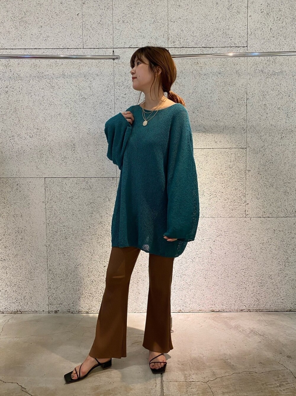 グリーン系のニット/セーター、ブラウン系のその他パンツ、ブラック系のサンダルを着用したレディースの春コーディネートの1枚目の写真