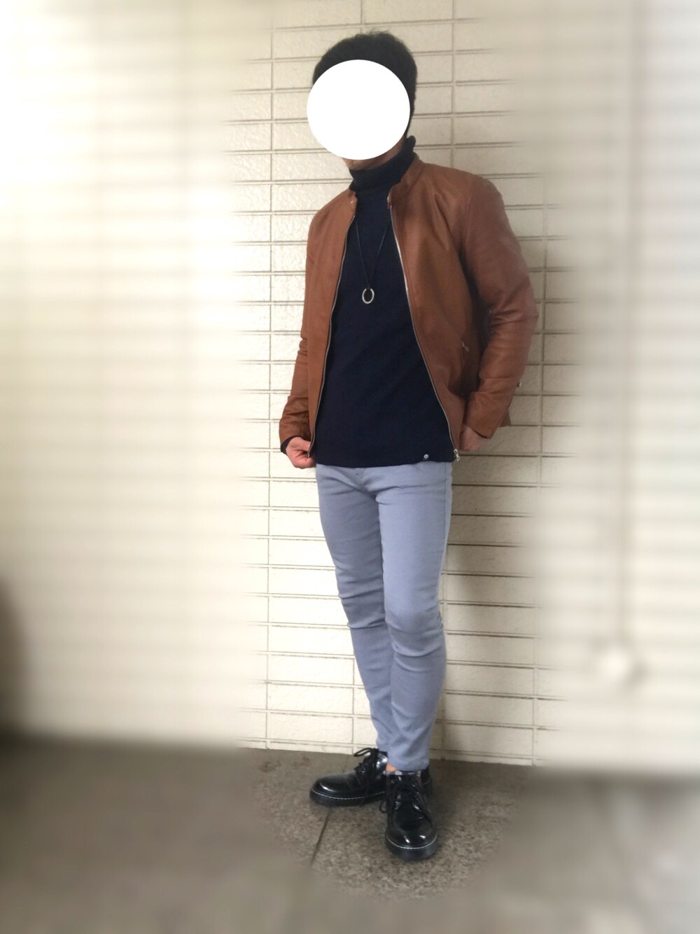 イエロー系のライダースジャケット、ブルー系のニット/セーター、グレー系のチノパンツを着用したメンズの秋コーディネートの1枚目の写真