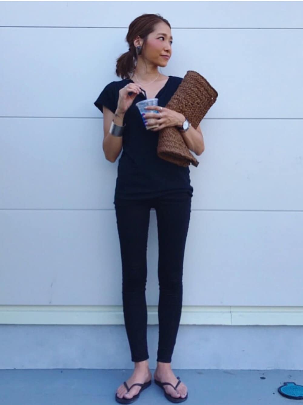 ブラック系のTシャツ/カットソー、ブラウン系のクラッチバッグ、ブラック系のサンダルを着用したレディースの夏コーディネートの1枚目の写真