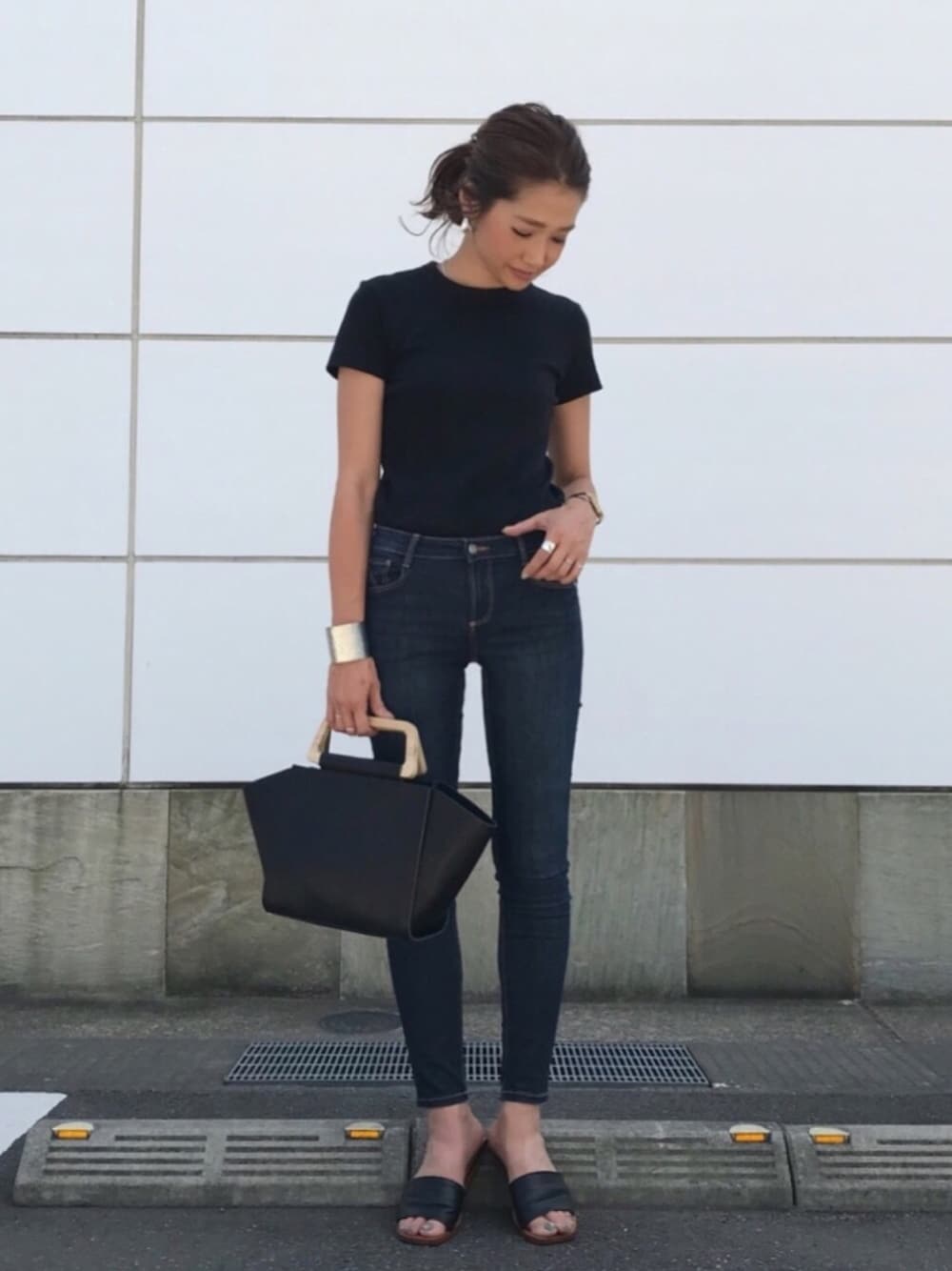 ブラック系のトートバッグ、ブラック系のサンダル、ブルー系のデニムパンツを着用したレディースの夏コーディネートの1枚目の写真