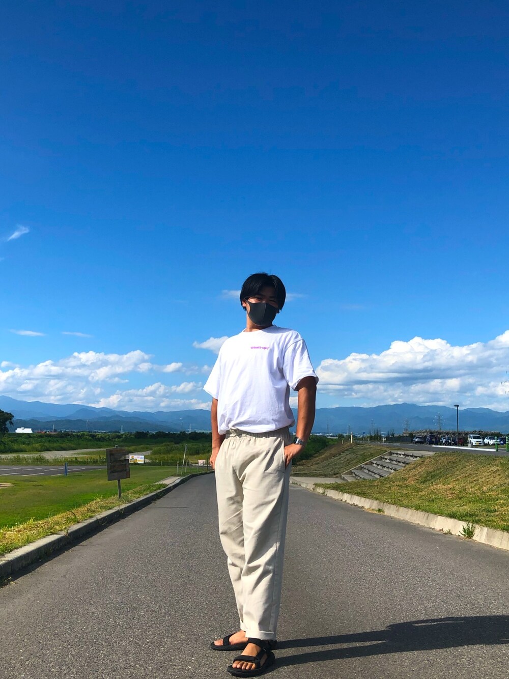 ホワイト系のTシャツ/カットソー、ベージュ系のパンツ、ブラック系のサンダルを着用したメンズの夏コーディネートの1枚目の写真