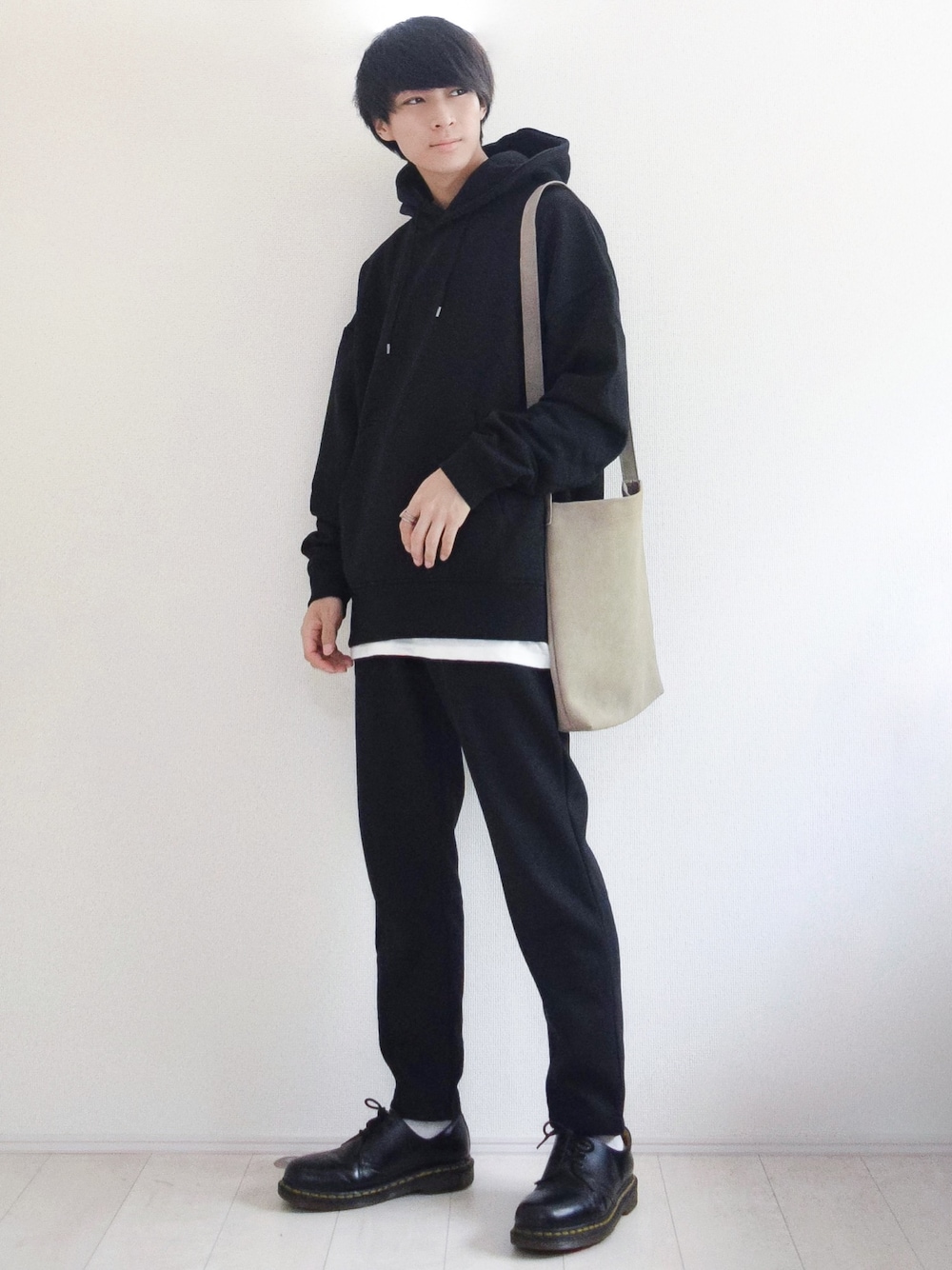 ホワイト系のタンクトップ、ベージュ系のショルダーバッグ、ブラック系のブーツを着用したメンズの秋コーディネートの1枚目の写真