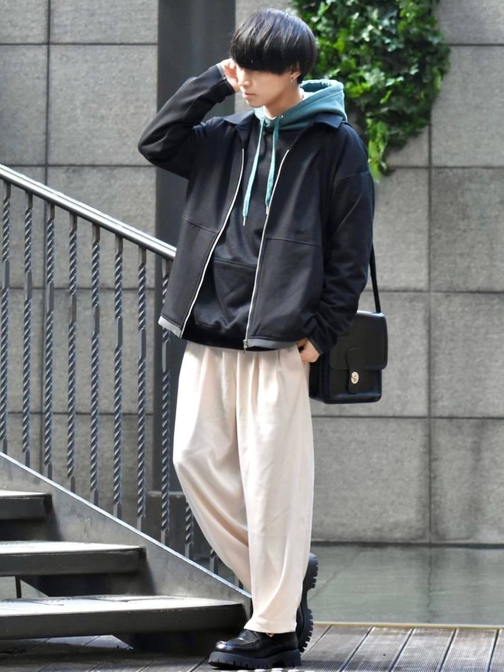 ブラック系のブルゾン、ブラック系のパーカー、ベージュ系のスーツパンツを着用したメンズの冬コーディネートの1枚目の写真