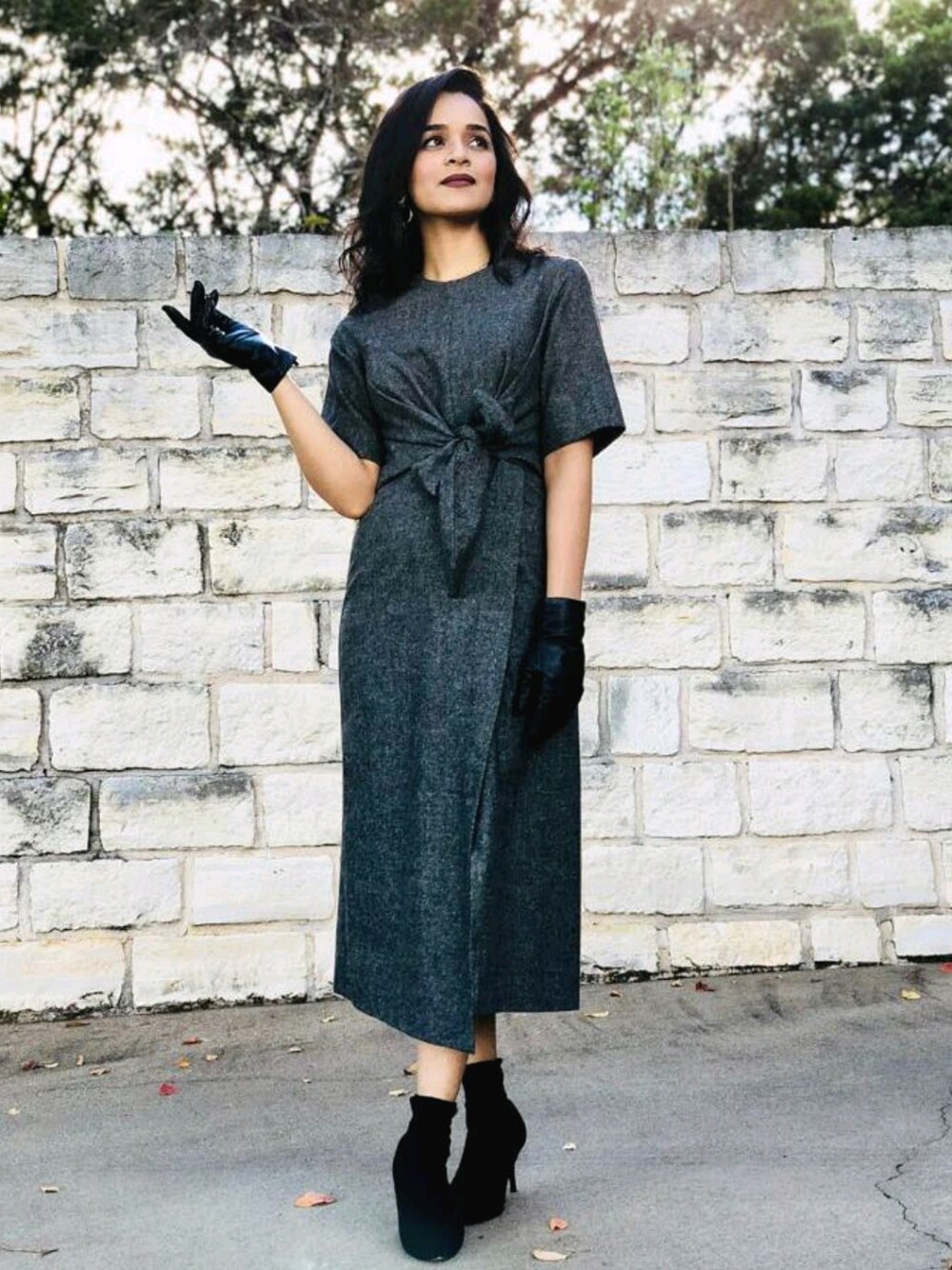 グレー系のドレス、ブラック系のブーツ、ブラック系の手袋を着用したレディースの冬コーディネートの1枚目の写真