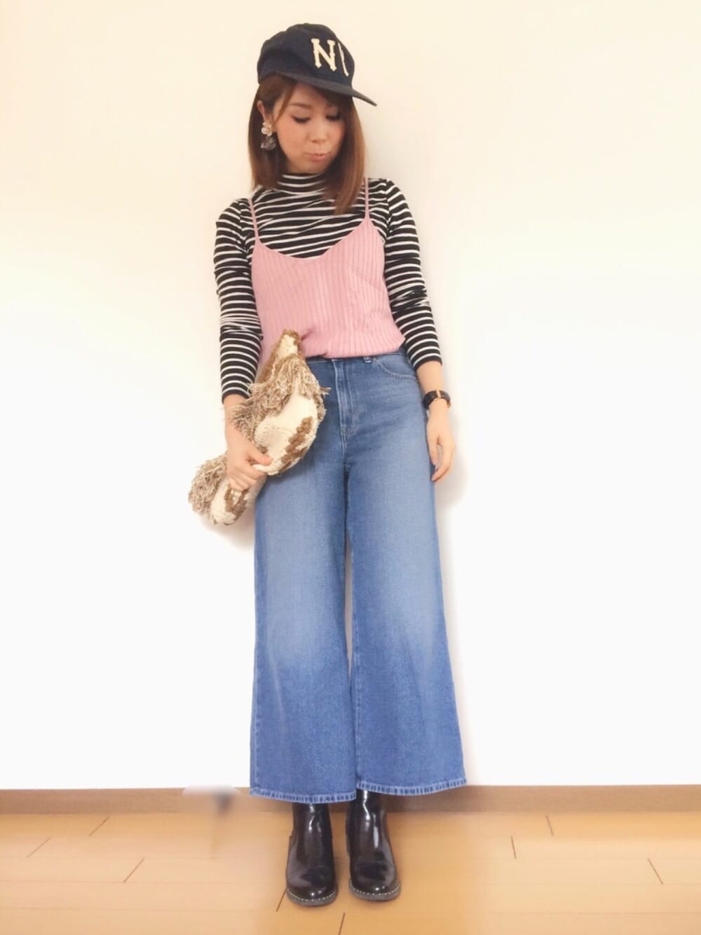 ピンク系のキャミソール、ブルー系のデニムパンツ、イエロー系のクラッチバッグを着用したレディースの春コーディネートの1枚目の写真