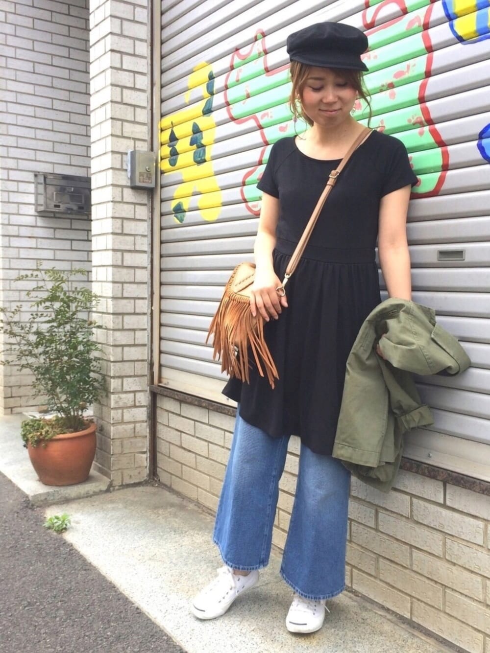 ブラック系のワンピース、ブラウン系のショルダーバッグ、ブルー系のデニムパンツを着用したレディースの春コーディネートの1枚目の写真