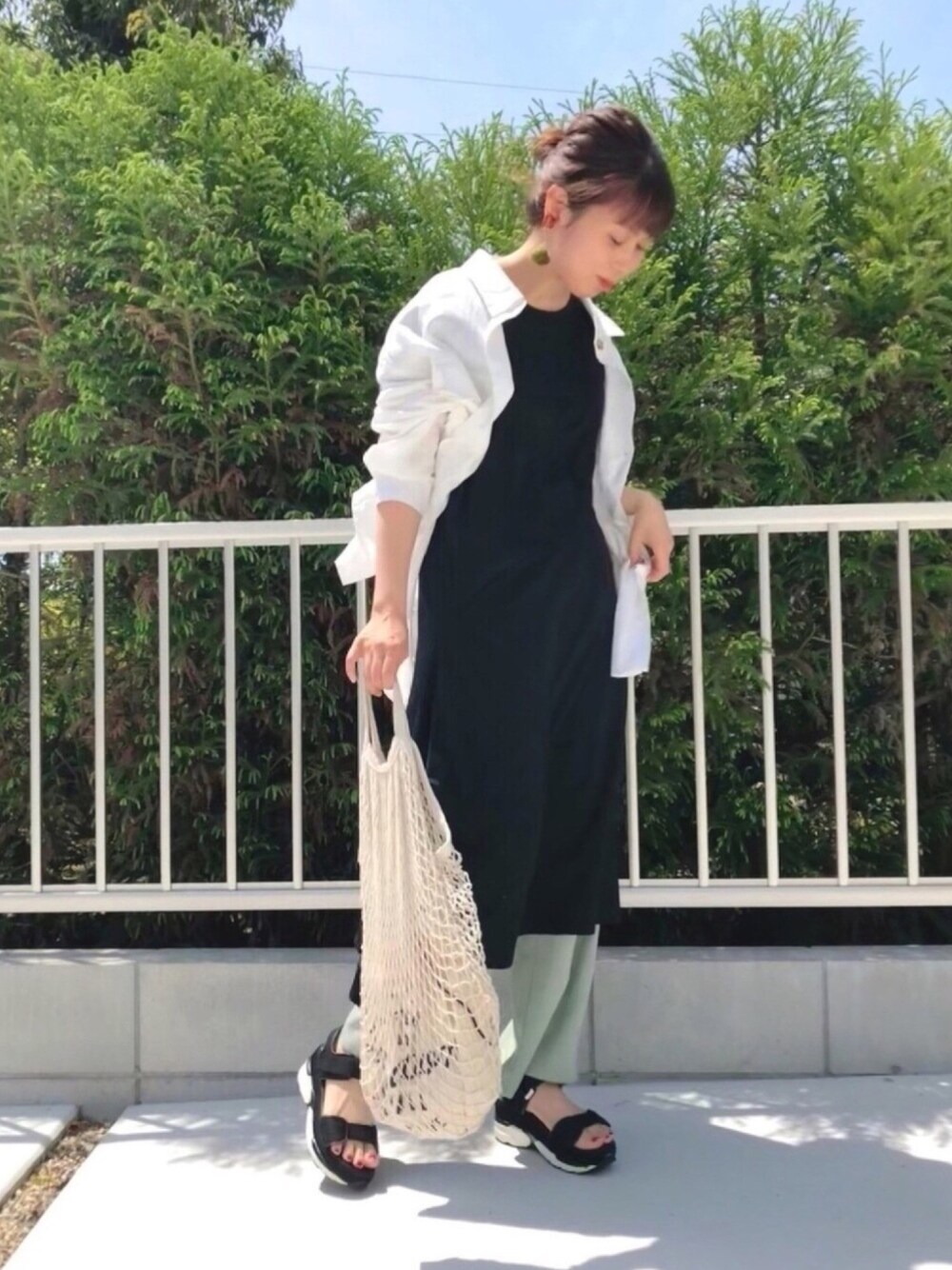 ホワイト系のシャツ/ブラウス、ブラック系のワンピース、グリーン系のその他パンツを着用したレディースの春コーディネートの1枚目の写真