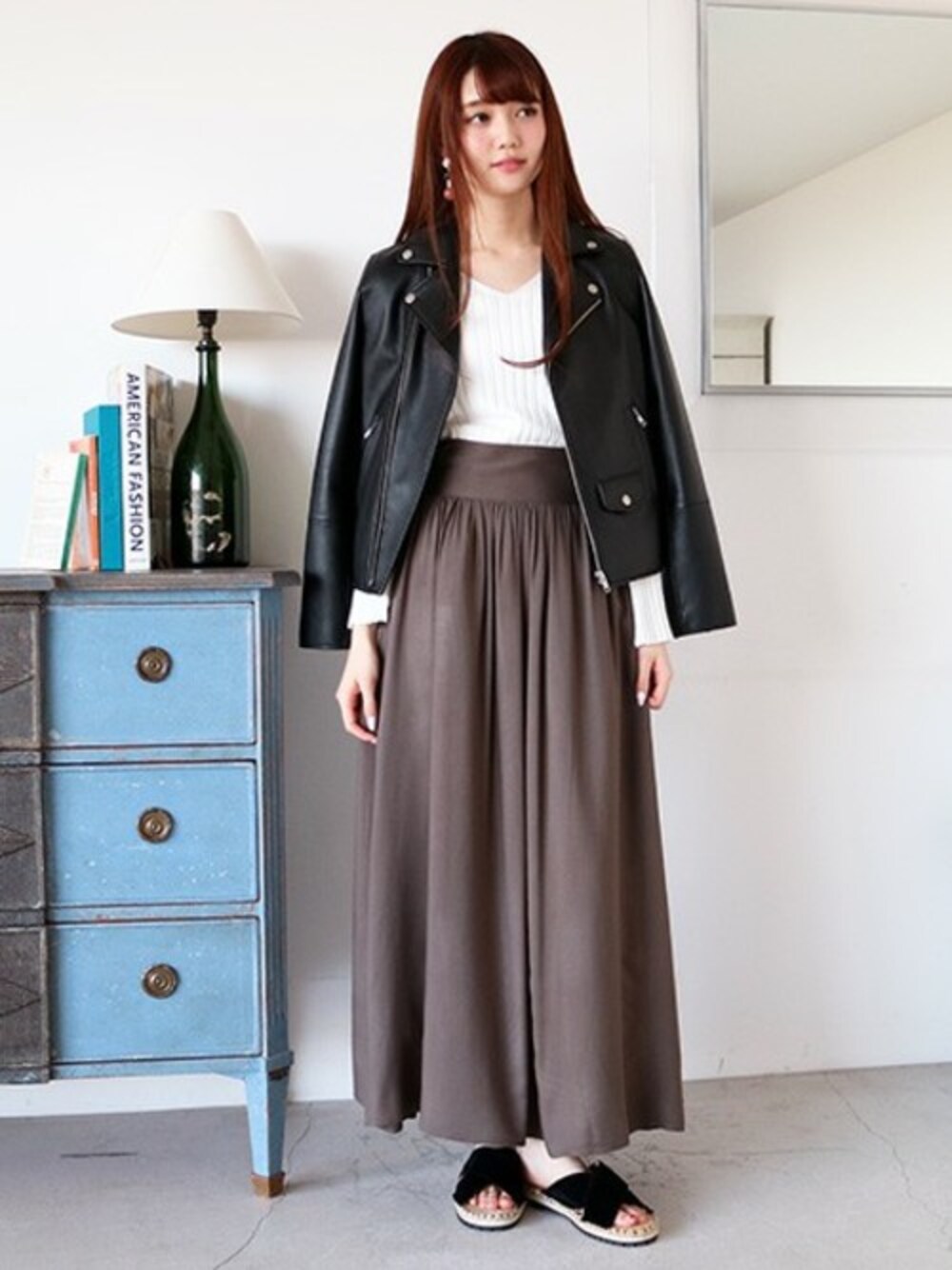 ブラック系のライダースジャケット、グリーン系のスカート、ブラック系のサンダルを着用したレディースの冬コーディネートの1枚目の写真