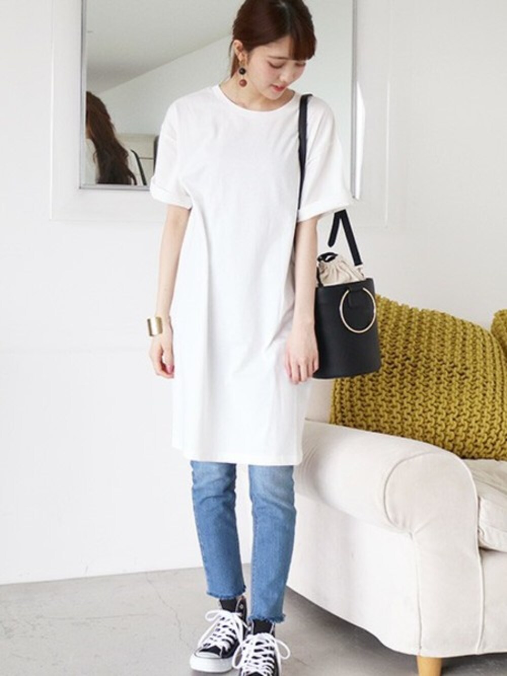 ホワイト系のシャツワンピース、ブルー系のデニムパンツ、ブラック系のトートバッグを着用したレディースの春コーディネートの1枚目の写真