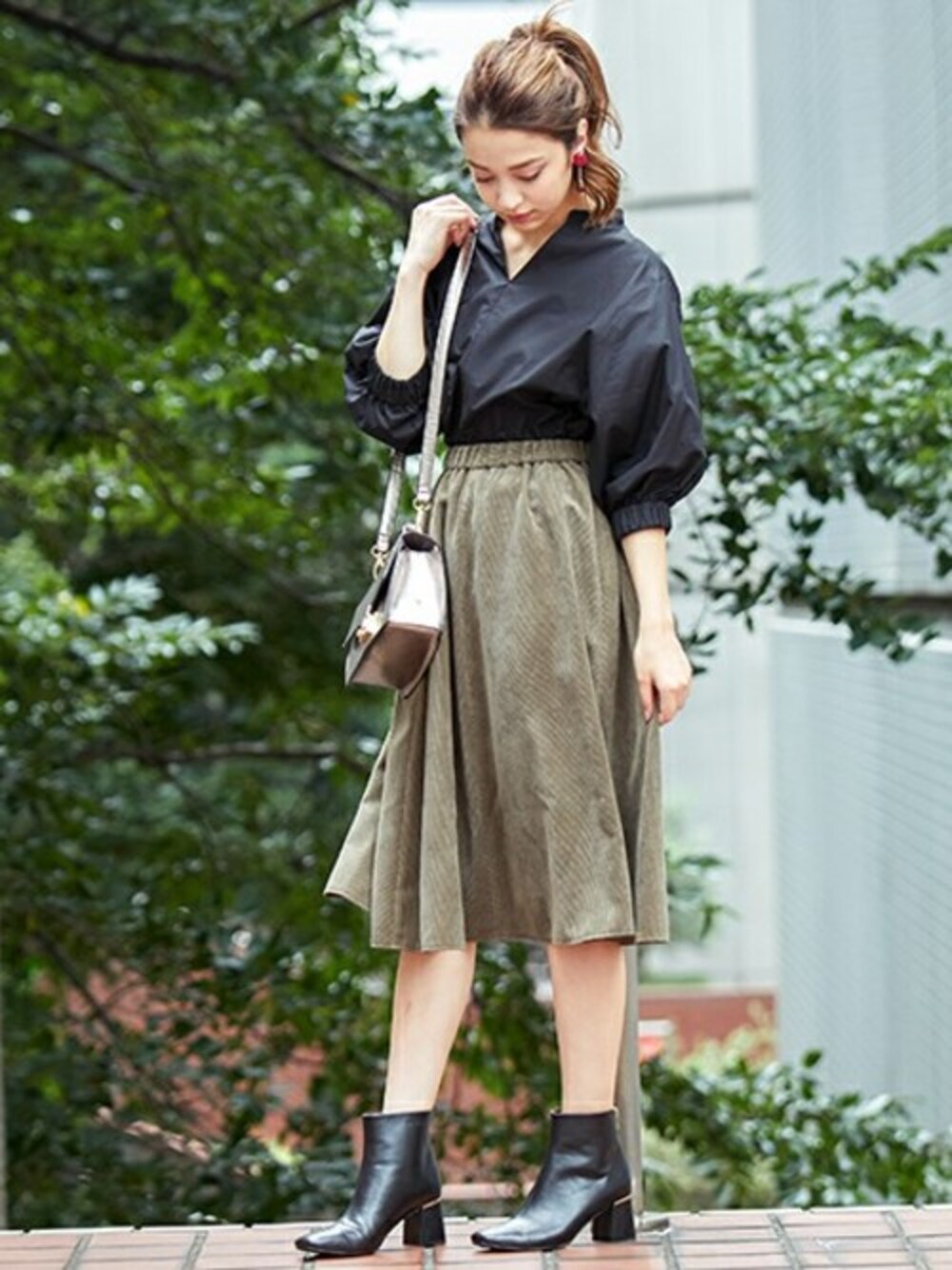 ブラック系のシャツ/ブラウス、グリーン系のスカート、シルバー系のショルダーバッグを着用したレディースの秋コーディネートの1枚目の写真