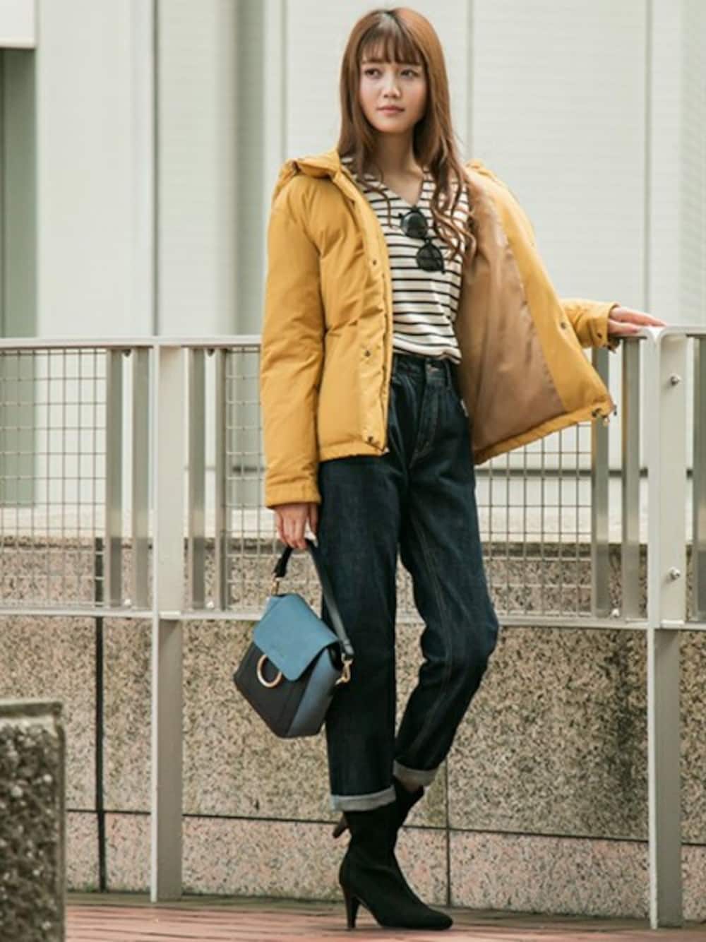 イエロー系のダウンジャケット/コート、ホワイト系のニット/セーター、ブルー系のデニムパンツを着用したレディースの秋コーディネートの1枚目の写真