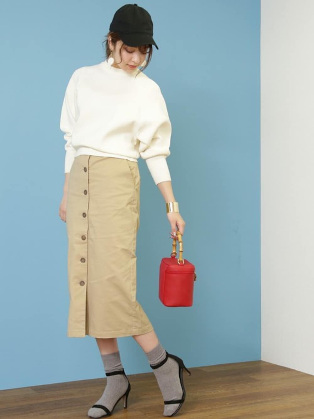 ベージュ系のスカート、レッド系のハンドバッグ、ゴールド系のバングル/リストバンドを着用したレディースの冬コーディネートの1枚目の写真