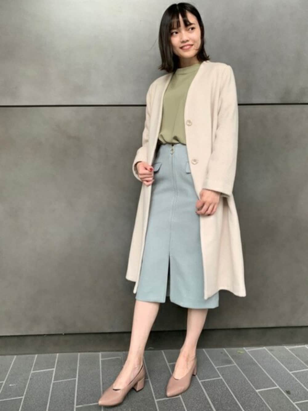 ホワイト系のノーカラーコート、イエロー系のシャツ/ブラウス、グリーン系のスカートを着用したレディースの秋コーディネートの1枚目の写真