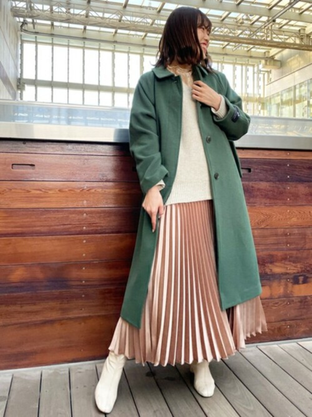 グリーン系のステンカラーコート、ホワイト系のニット/セーター、ホワイト系のTシャツ/カットソーを着用したレディースの冬コーディネートの1枚目の写真