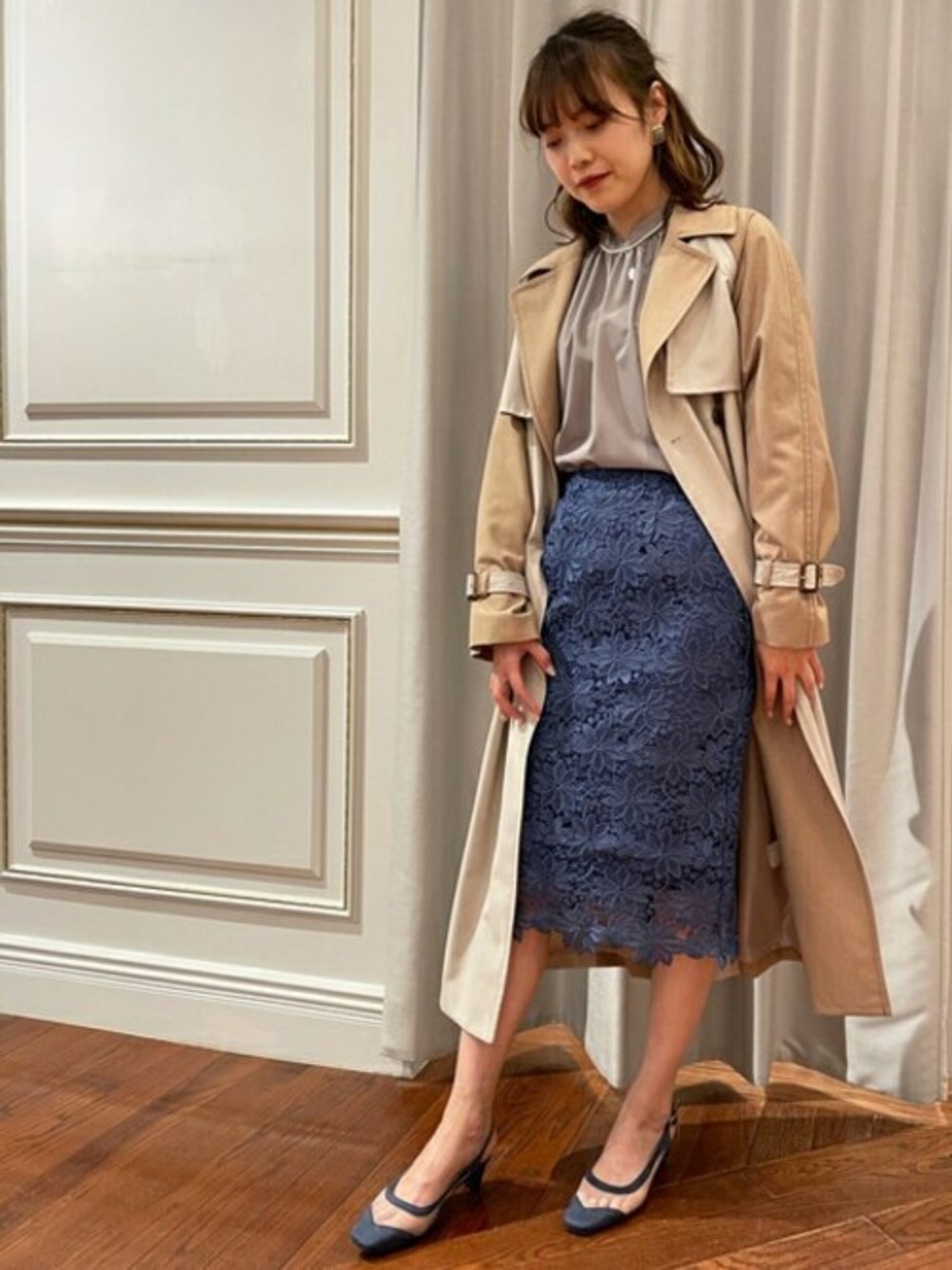 グレー系のシャツ/ブラウス、ベージュ系のトレンチコート、ブルー系のスカートを着用したレディースの冬コーディネートの1枚目の写真