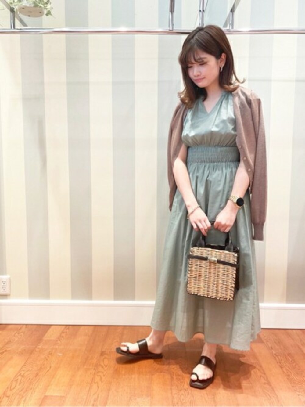 グリーン系のワンピース、ブラック系のサンダル、ベージュ系のカーディガン/ボレロを着用したレディースの春コーディネートの1枚目の写真