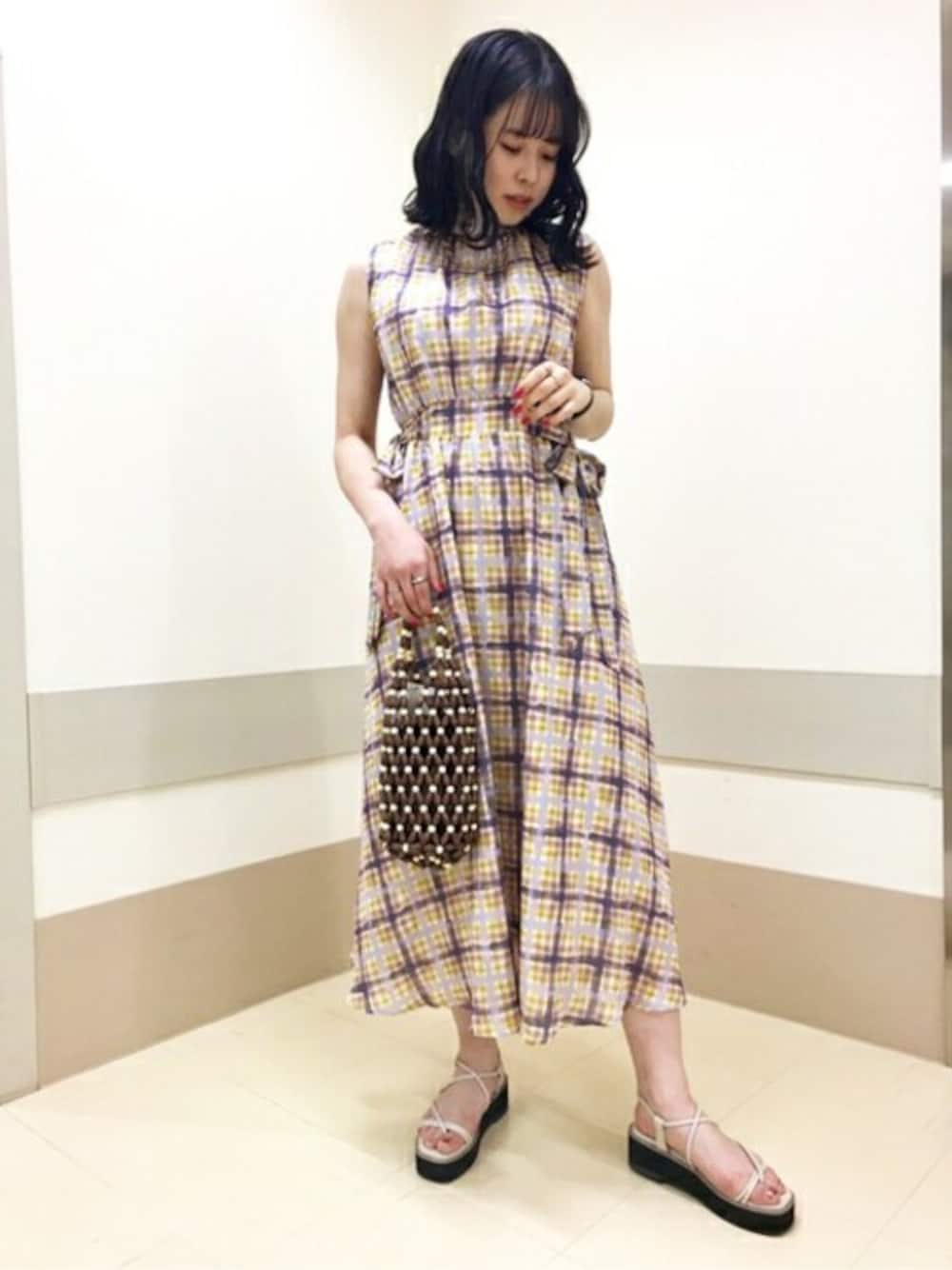 イエロー系のワンピース、ベージュ系のサンダル、ブラウン系のショルダーバッグを着用したレディースの春コーディネートの1枚目の写真