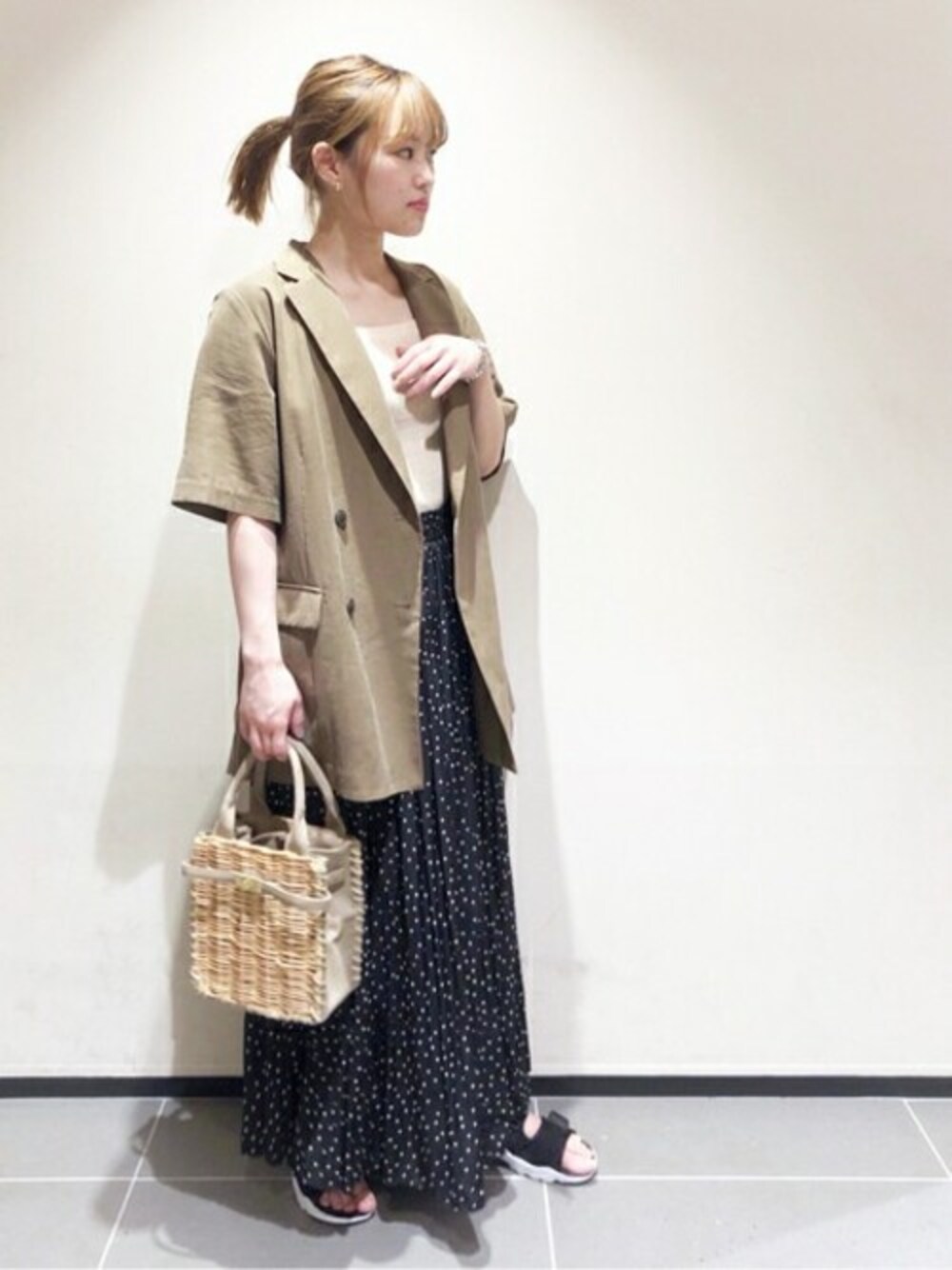 グリーン系のテーラードジャケット、ホワイト系のタンクトップ、ブラック系のスカートを着用したレディースの春コーディネートの1枚目の写真