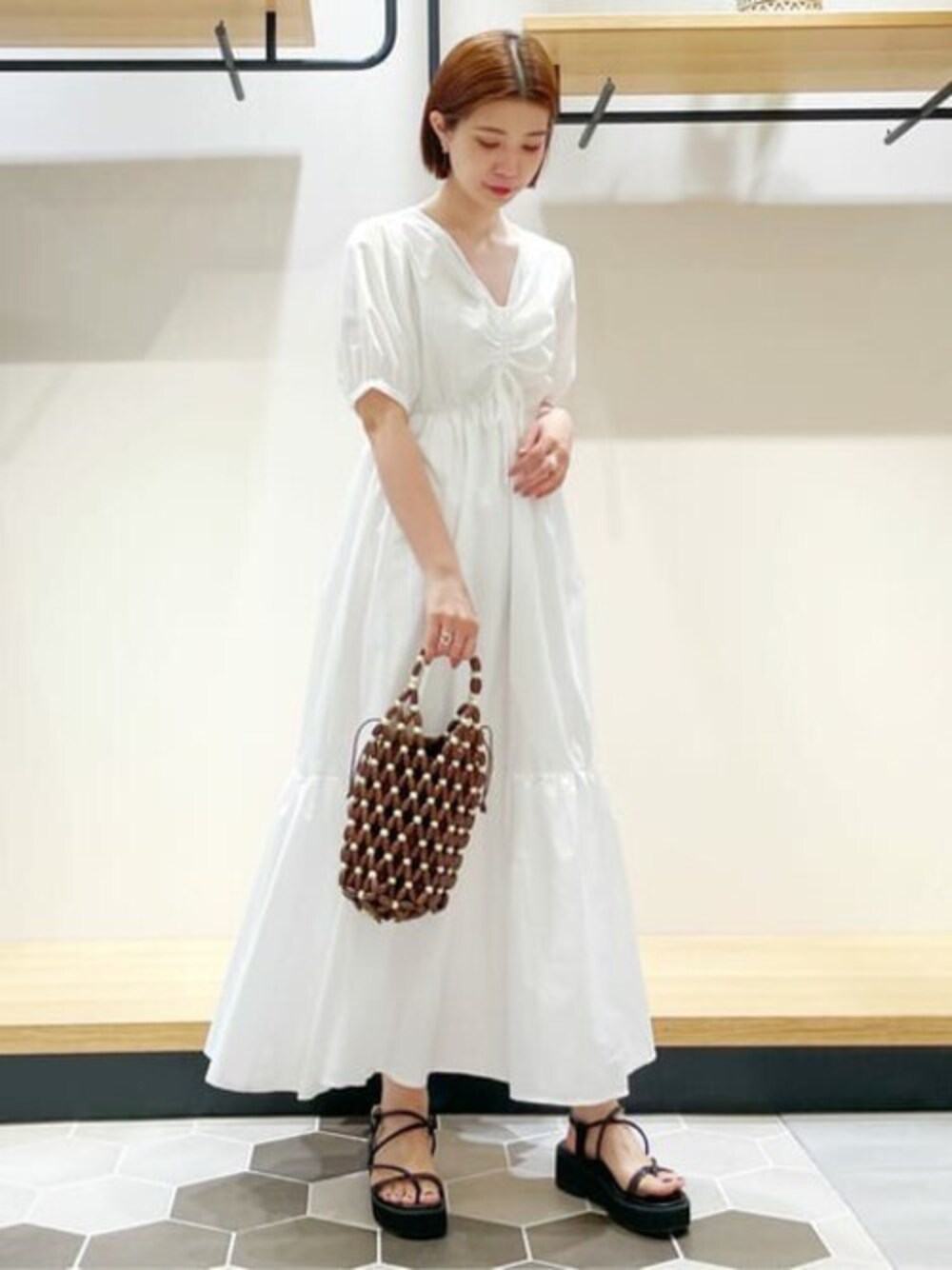 ホワイト系のワンピース、ブラック系のサンダル、ブラウン系のショルダーバッグを着用したレディースの夏コーディネートの1枚目の写真