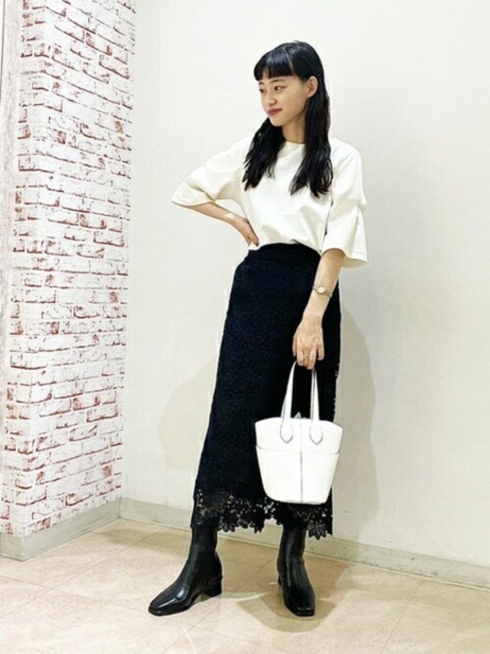 ブラック系のスカート、ブラック系のブーツ、ホワイト系のトートバッグを着用したレディースの夏コーディネートの1枚目の写真