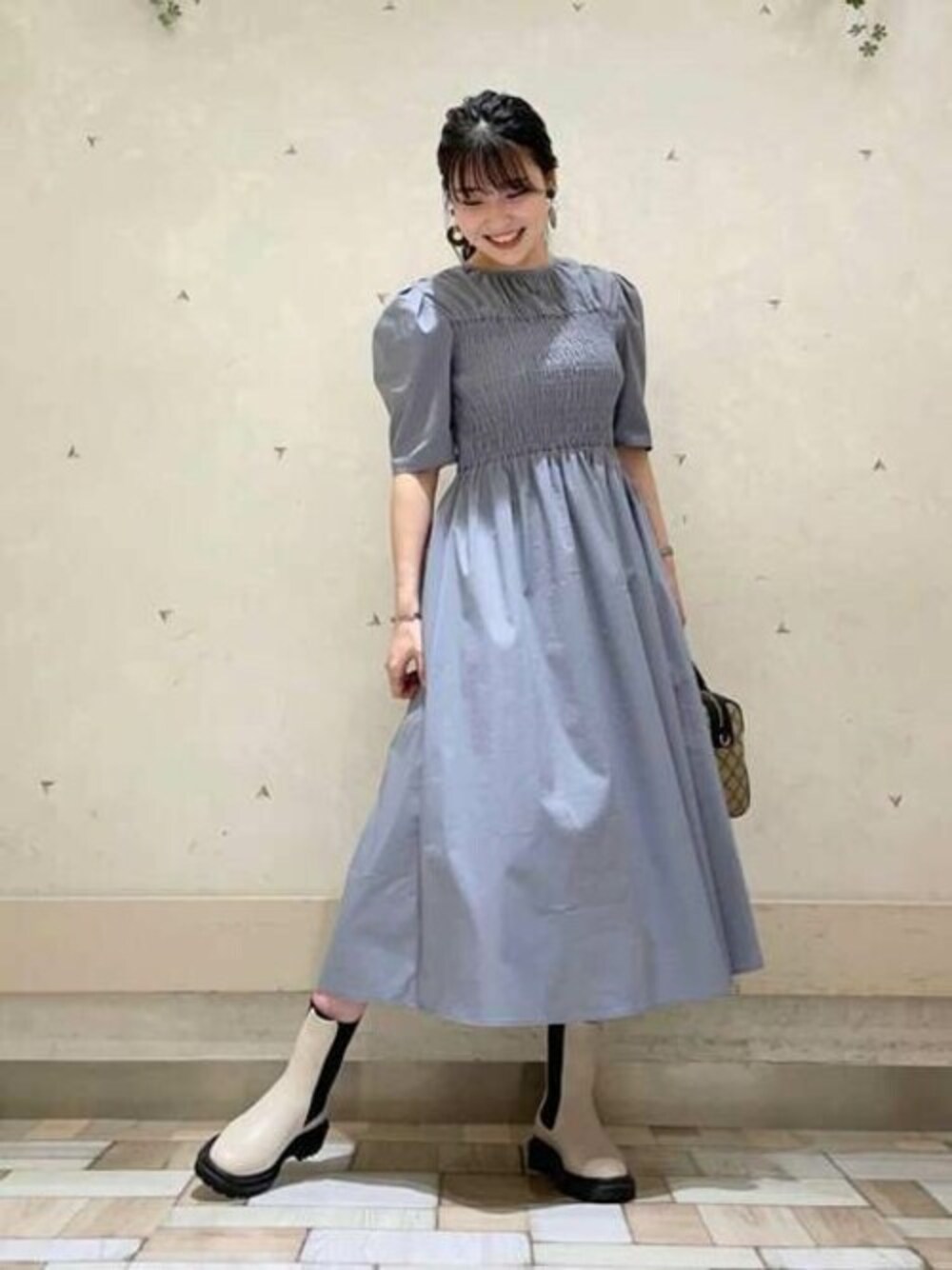 ブルー系のワンピース、ホワイト系のブーツ、ブラック系のボストンバッグを着用したレディースの秋コーディネートの1枚目の写真