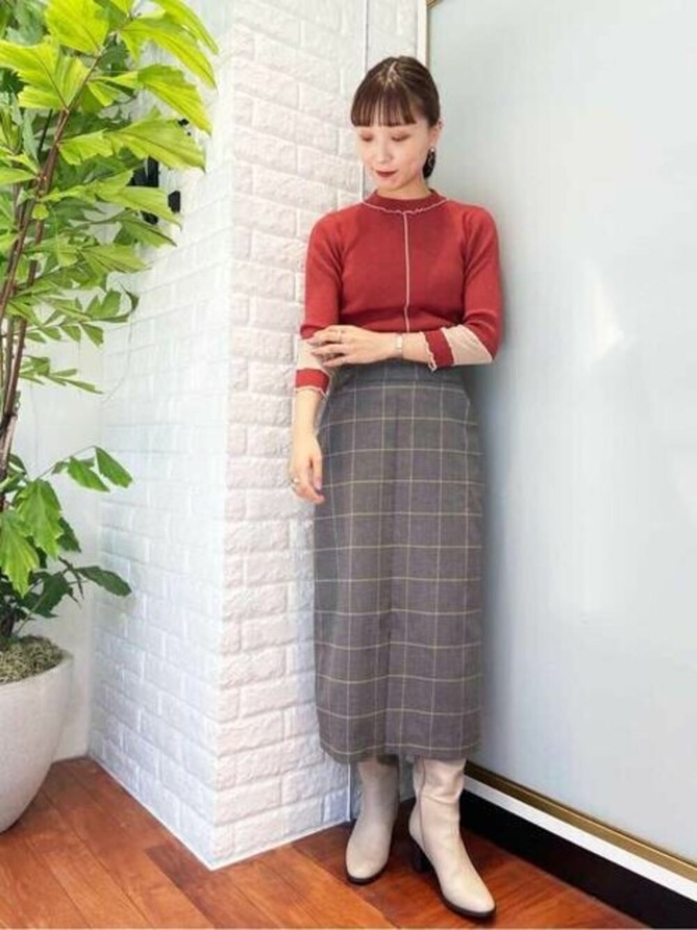 レッド系のニット/セーター、グレー系のスカート、ベージュ系のブーツを着用したレディースの秋コーディネートの1枚目の写真