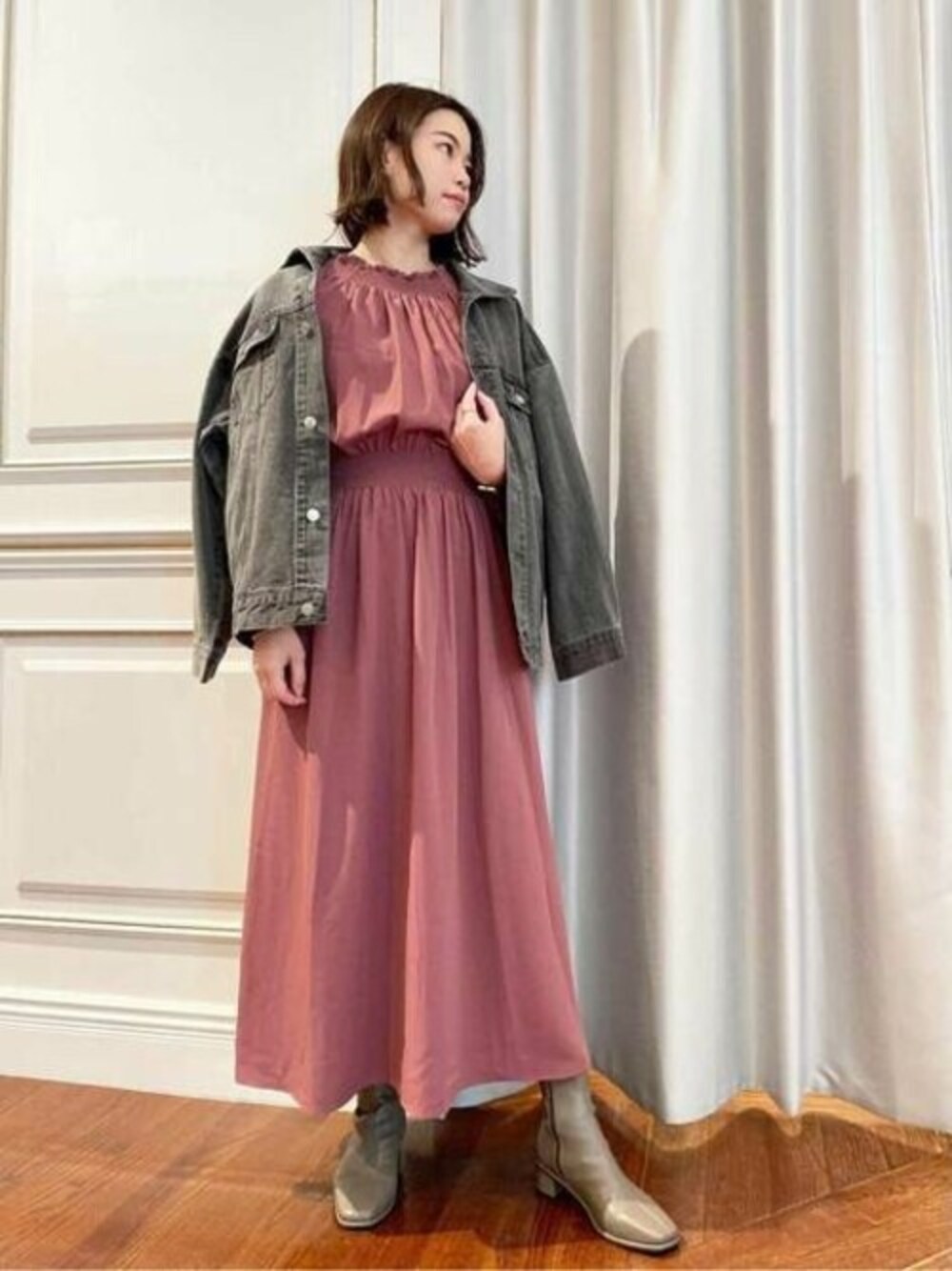 ピンク系のワンピース、ブラウン系のブーツ、グレー系のデニムジャケットを着用したレディースの秋コーディネートの1枚目の写真