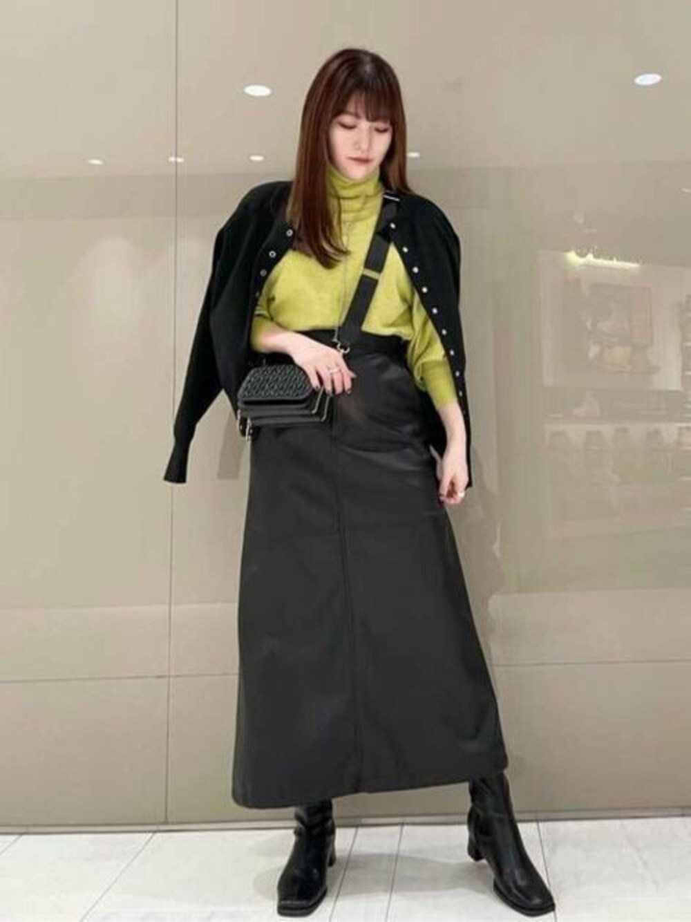 ブラック系のカーディガン/ボレロ、イエロー系のニット/セーター、ブラック系のスカートを着用したレディースの冬コーディネートの1枚目の写真