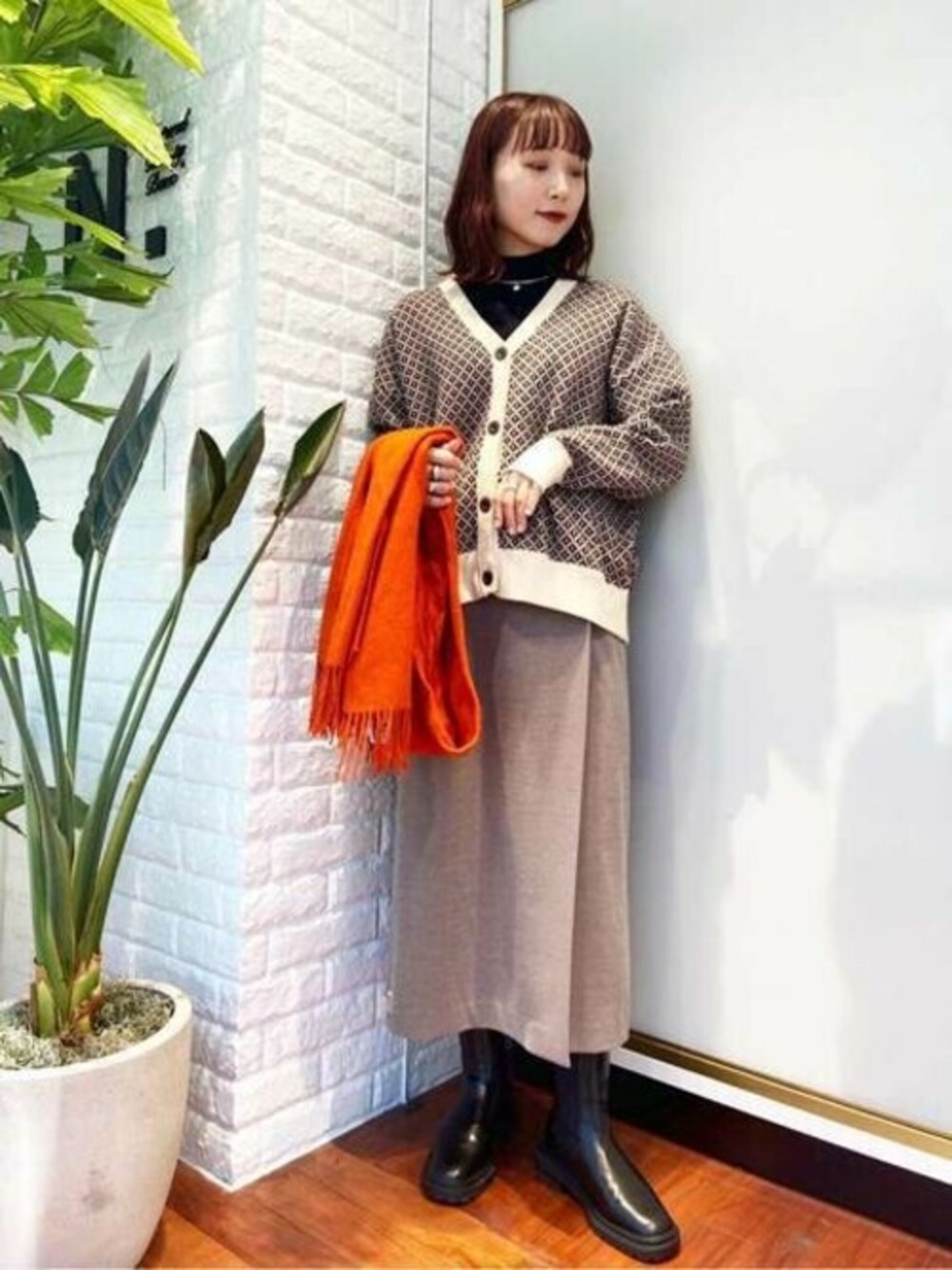 ホワイト系のカーディガン/ボレロ、ブラウン系のスカート、ブラック系のブーツを着用したレディースの冬コーディネートの1枚目の写真