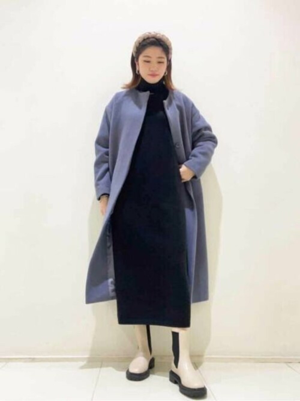 ブラック系のワンピース、ブルー系のノーカラーコート、ホワイト系のブーツを着用したレディースの冬コーディネートの1枚目の写真