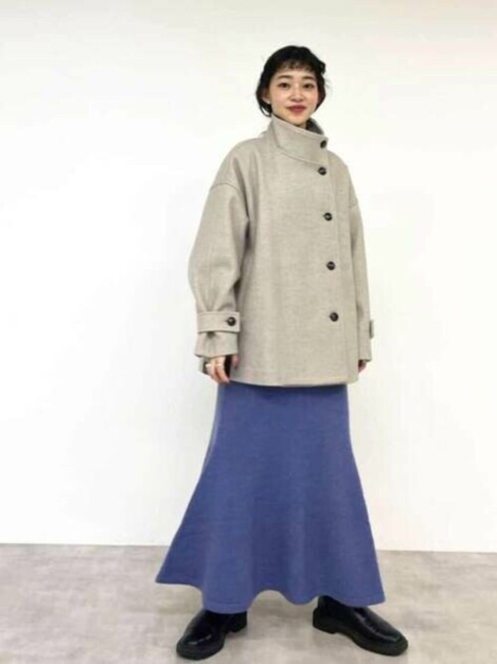 ブルー系のワンピース、ベージュ系のその他アウター、ブラック系のブーツを着用したレディースの冬コーディネートの1枚目の写真