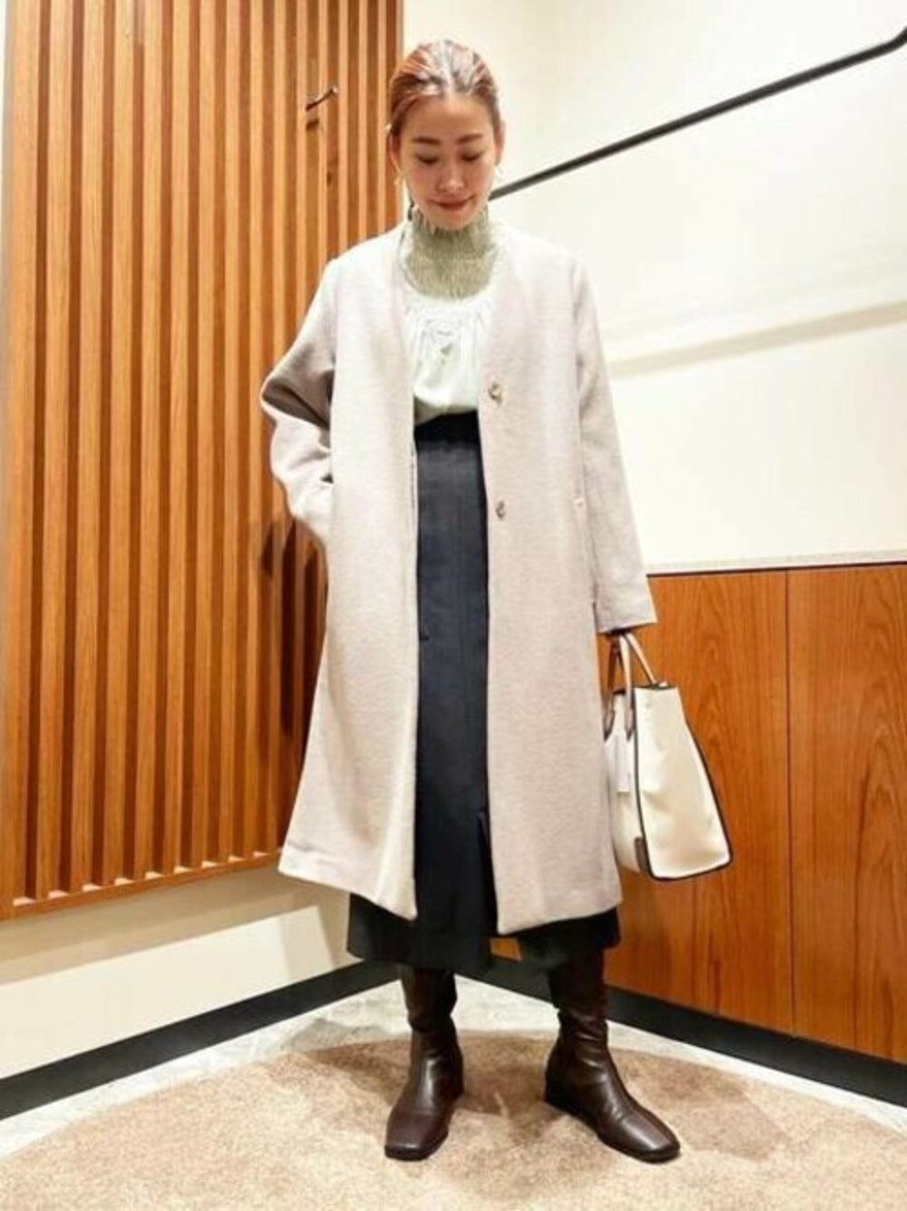 グレー系のスカート、グリーン系のシャツ/ブラウス、ベージュ系のトートバッグを着用したレディースの冬コーディネートの1枚目の写真