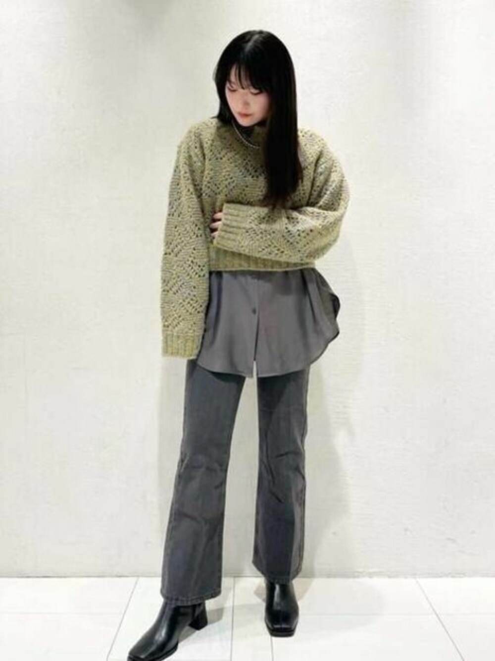 イエロー系のニット/セーター、グレー系のシャツ/ブラウス、グレー系のデニムパンツを着用したレディースの冬コーディネートの1枚目の写真