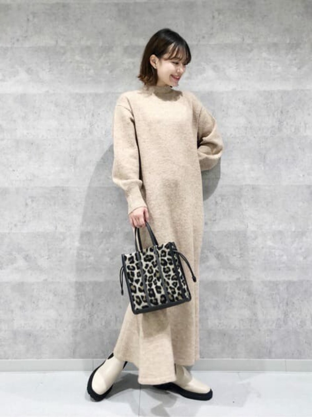 ベージュ系のワンピース、ホワイト系のブーツ、ブラウン系のトートバッグを着用したレディースの冬コーディネートの1枚目の写真