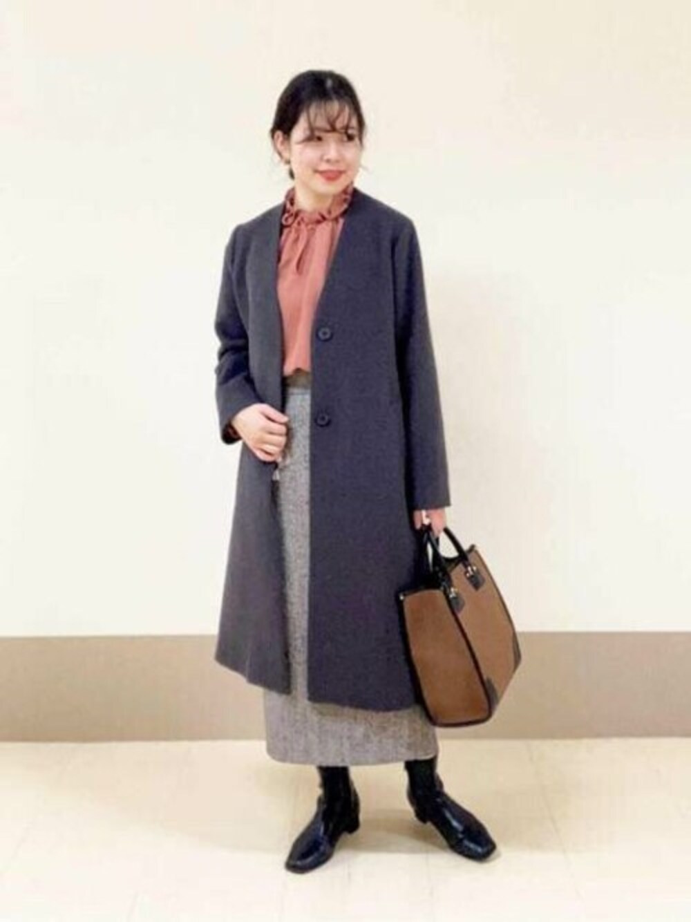 ブラウン系のトートバッグ、ブラウン系のスカート、グレー系のノーカラーコートを着用したレディースの冬コーディネートの1枚目の写真