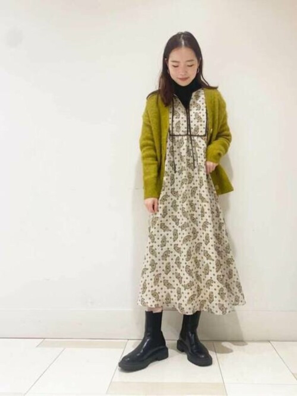 イエロー系のカーディガン/ボレロ、ホワイト系のワンピースを着用したレディースの冬コーディネートの1枚目の写真