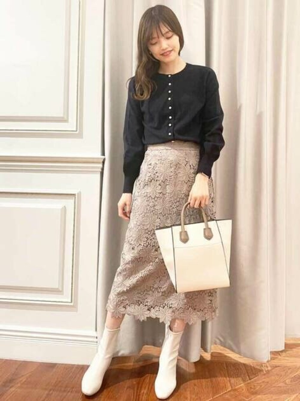 ベージュ系のトートバッグ、ベージュ系のスカート、ブルー系のカーディガン/ボレロを着用したレディースの冬コーディネートの1枚目の写真