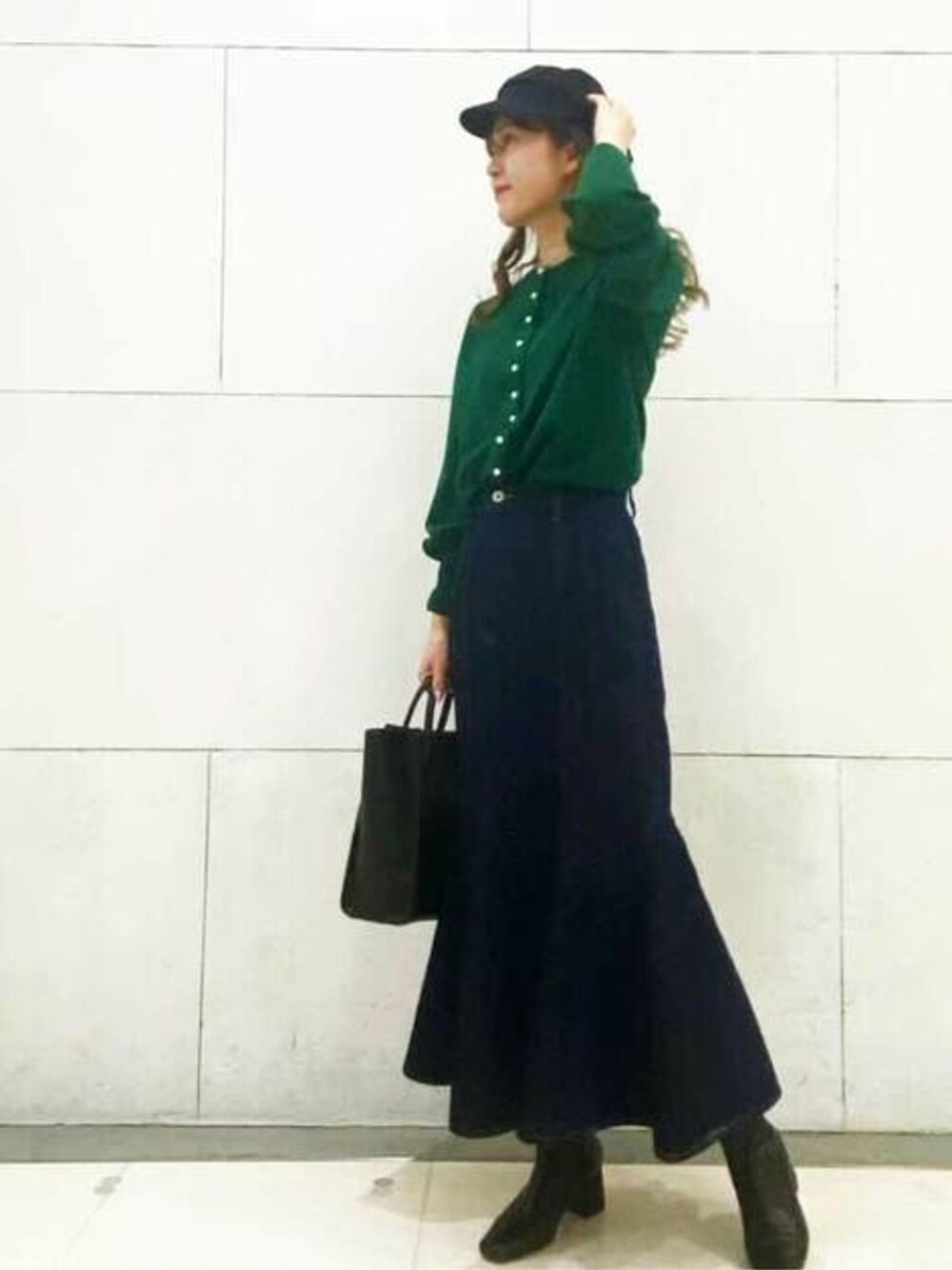 ブルー系のデニムスカート、グリーン系のカーディガン/ボレロ、ブラック系のトートバッグを着用したレディースの冬コーディネートの1枚目の写真
