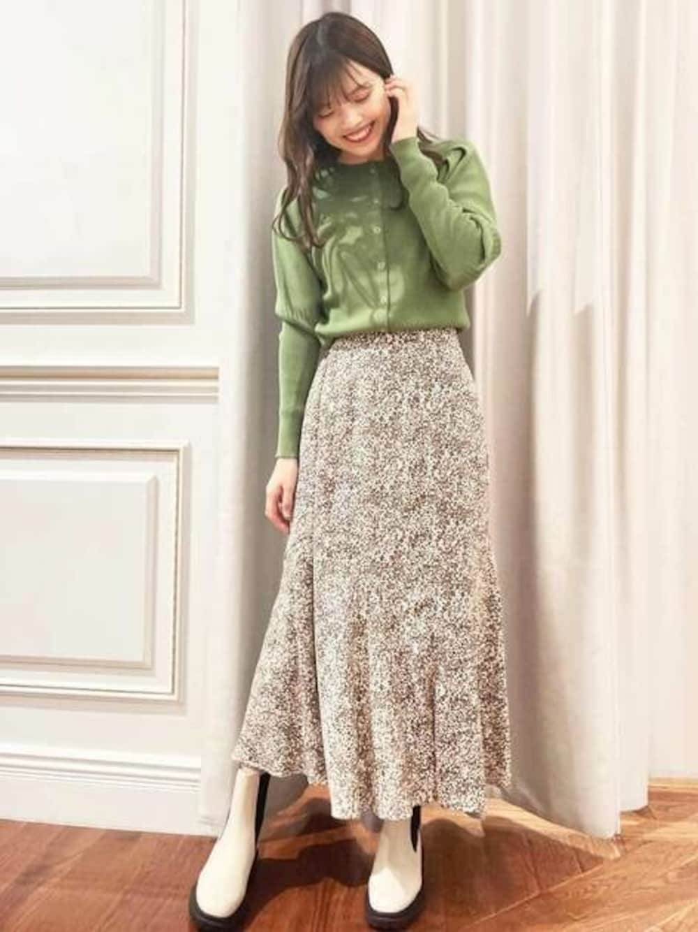 ホワイト系のスカート、グリーン系のカーディガン/ボレロ、ホワイト系のブーツを着用したレディースの冬コーディネートの1枚目の写真