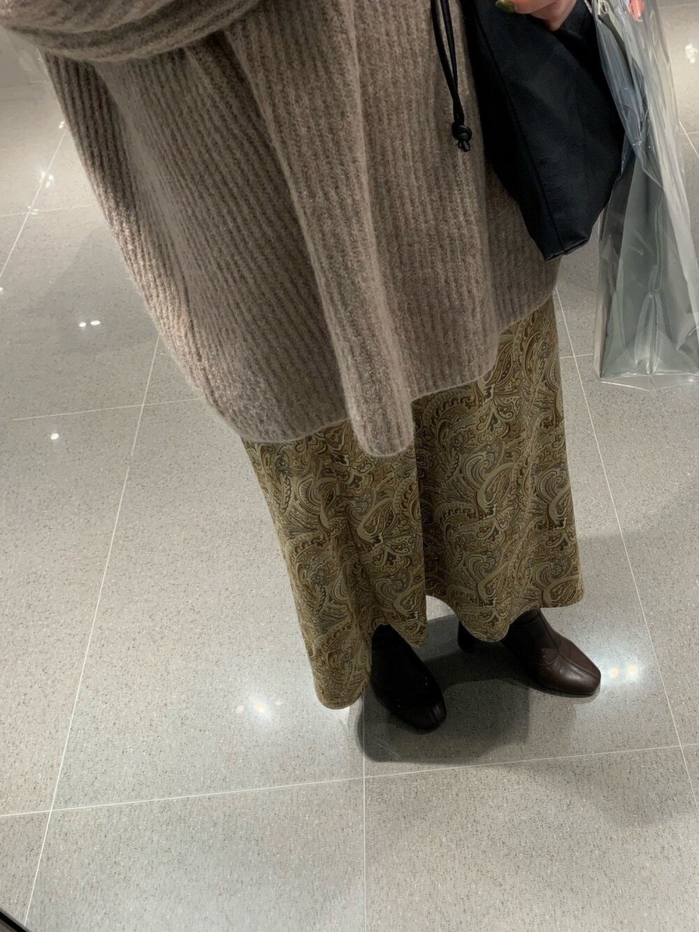 ベージュ系のニット/セーター、ベージュ系のスカート、ブラウン系のブーツを着用したレディースの冬コーディネートの1枚目の写真