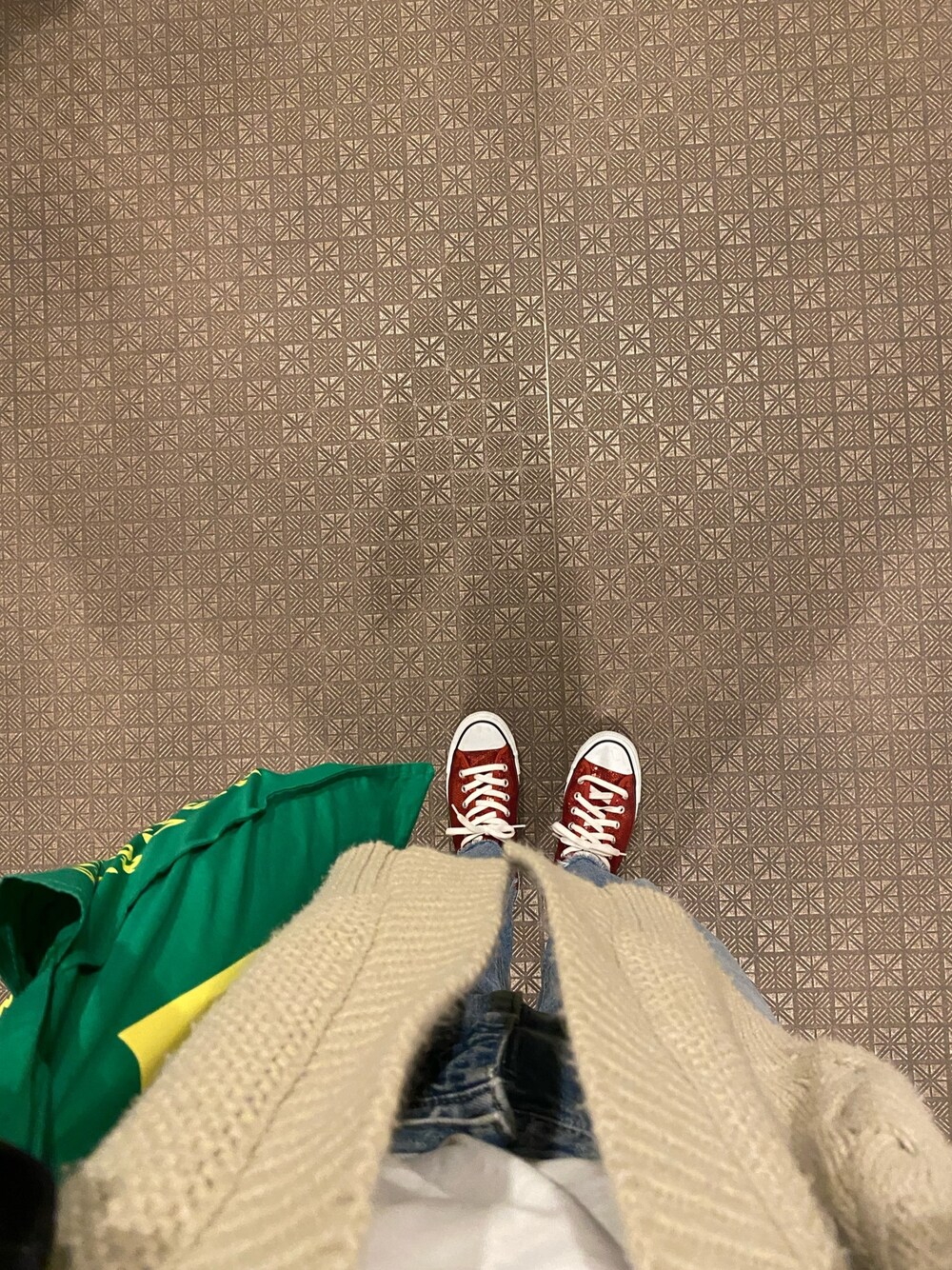 レッド系のスニーカー、ホワイト系のカーディガン/ボレロ、ブルー系のデニムパンツを着用したレディースの春コーディネートの1枚目の写真