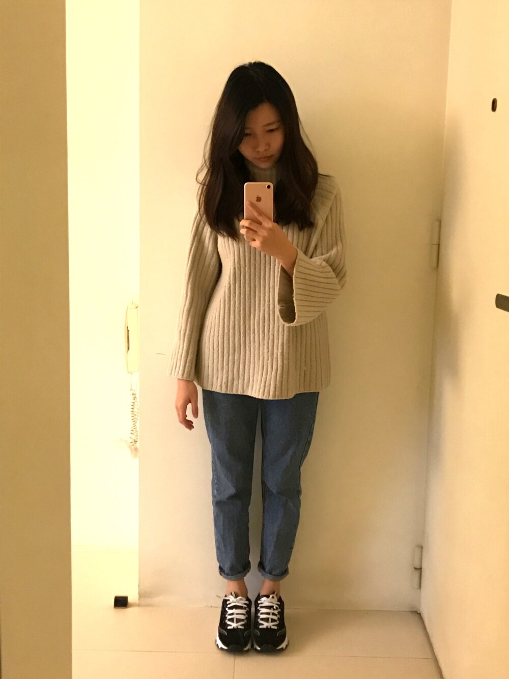 ブルー系のデニムパンツ、ブラック系のスニーカーを着用したレディースの春コーディネートの1枚目の写真