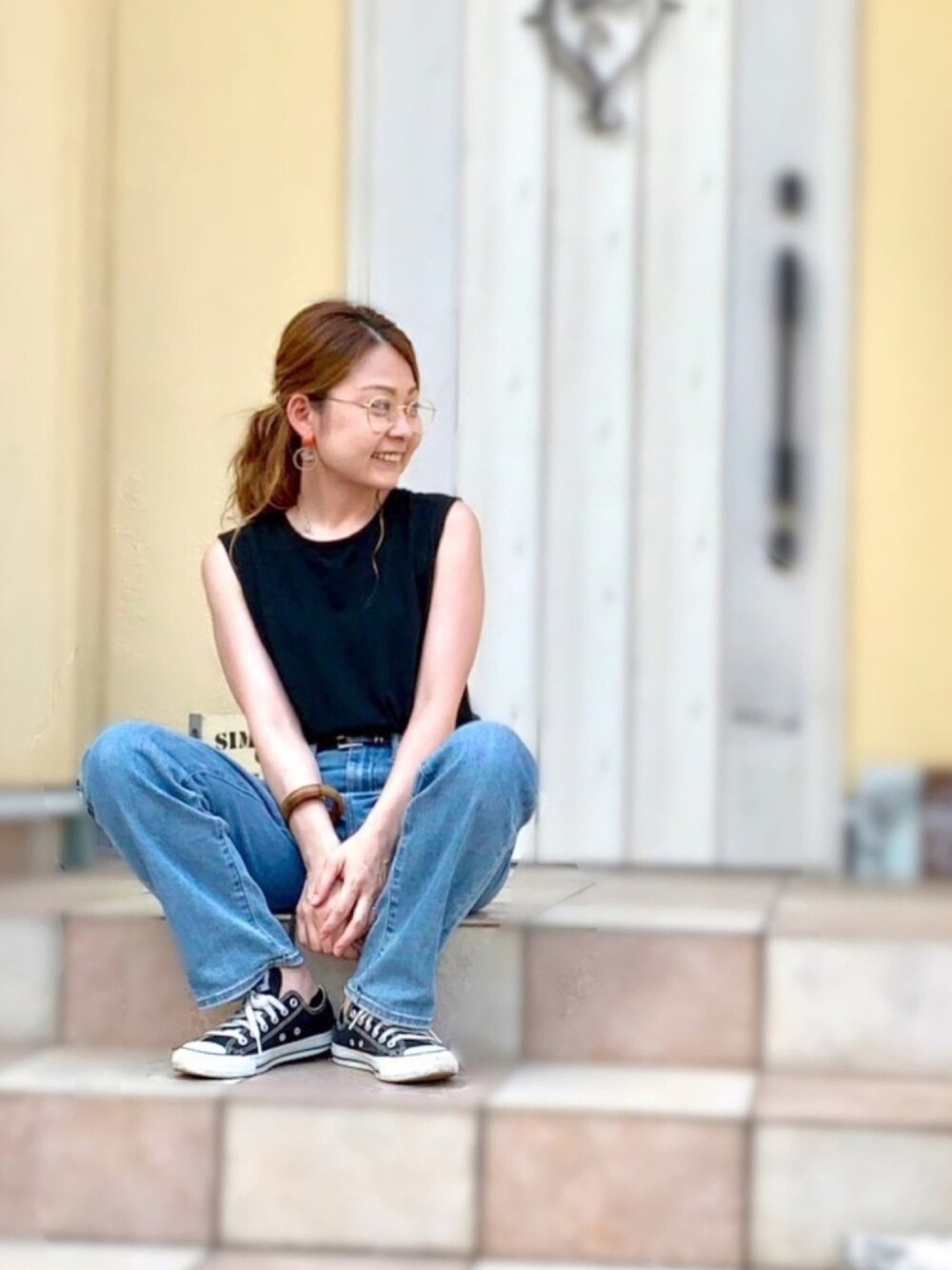 ブラック系のTシャツ/カットソー、ブルー系のデニムパンツ、ブラック系のスニーカーを着用したレディースの夏コーディネートの1枚目の写真