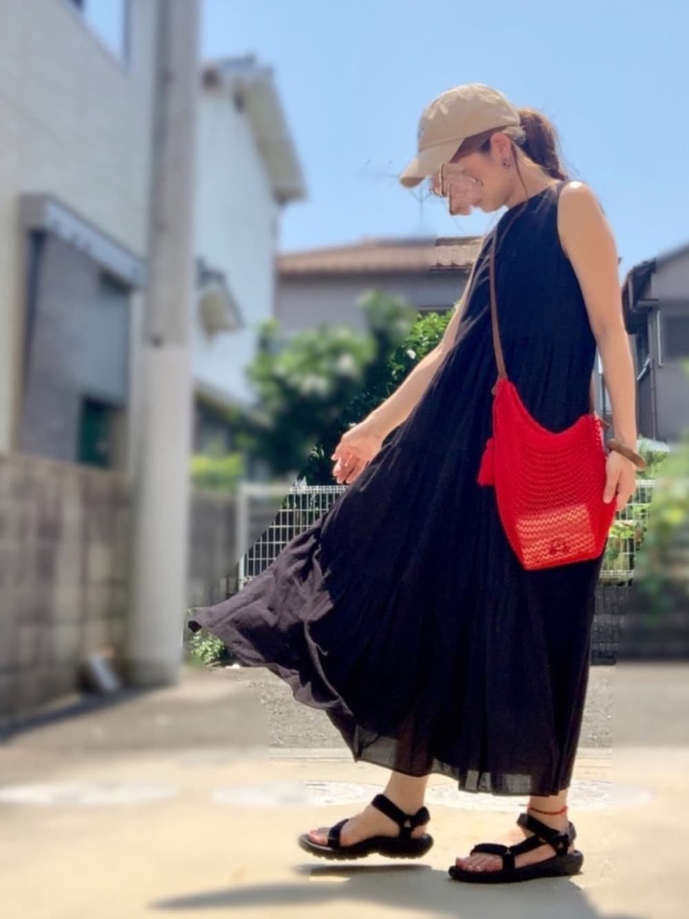 ブラック系のワンピース、レッド系のショルダーバッグ、ブラック系のサンダルを着用したレディースの夏コーディネートの1枚目の写真