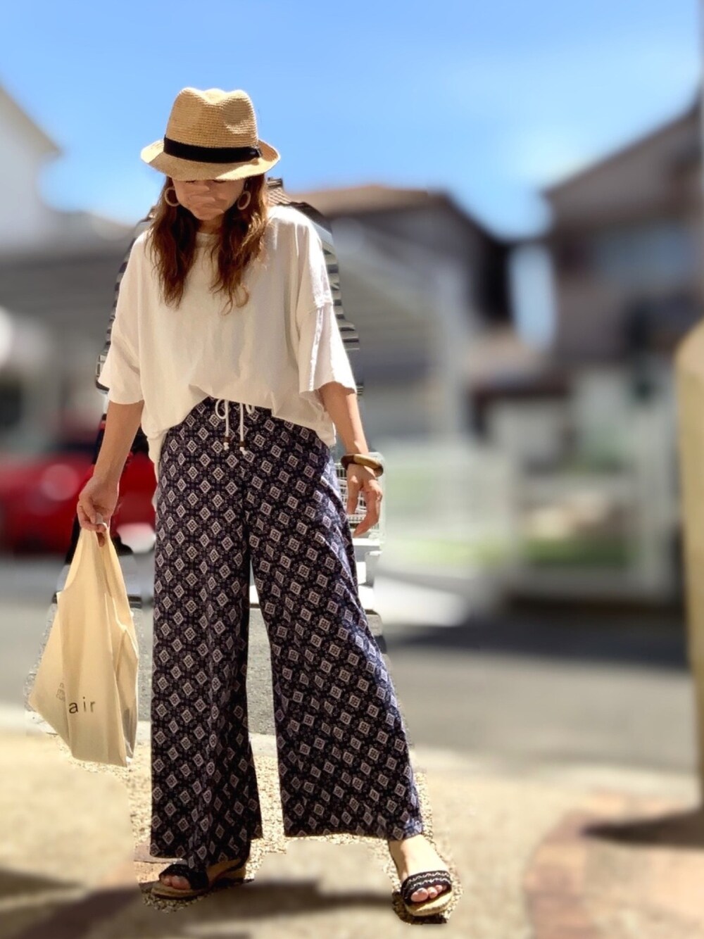 ホワイト系のTシャツ/カットソー、ベージュ系のトートバッグ、ブラック系のサンダルを着用したレディースの夏コーディネートの1枚目の写真