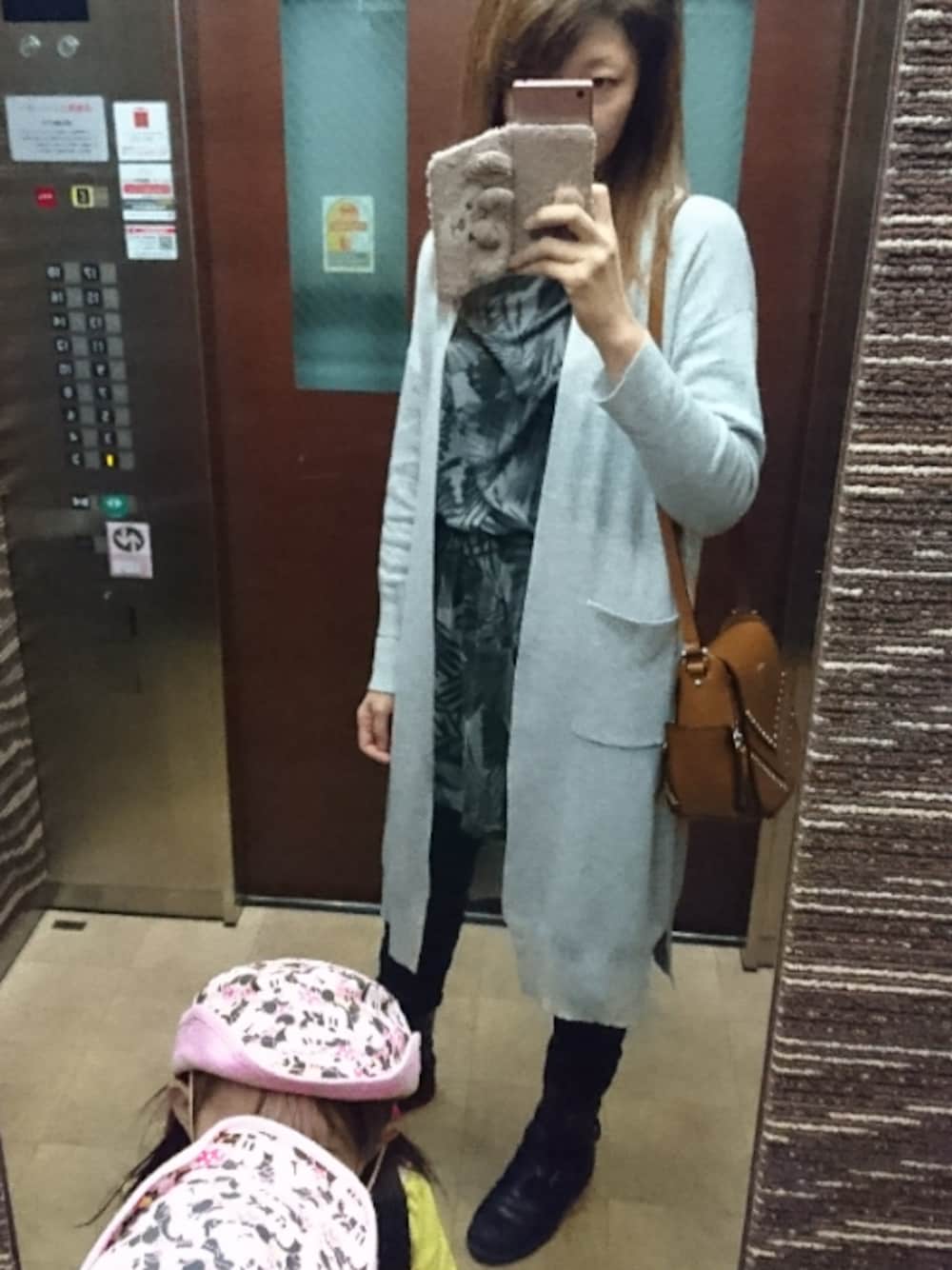 ブラック系のチュニック、グレー系のカーディガン/ボレロ、ブラック系のデニムパンツを着用したレディースの秋コーディネートの1枚目の写真