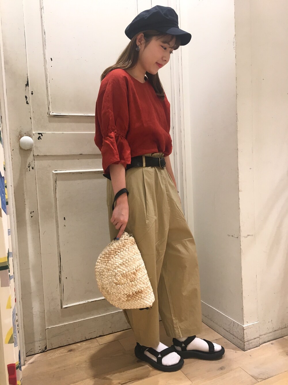 レッド系のトップス、ベージュ系のその他パンツ、ブルー系のキャップを着用したレディースの夏コーディネートの1枚目の写真