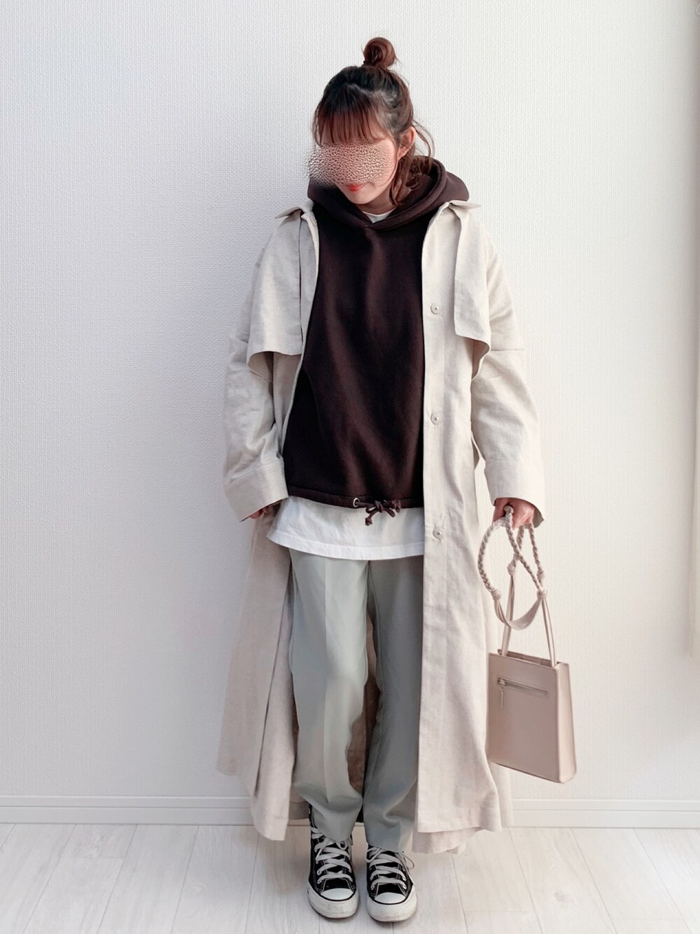 グレー系のパーカー、ベージュ系のステンカラーコート、グリーン系のパンツを着用したレディースの冬コーディネートの1枚目の写真