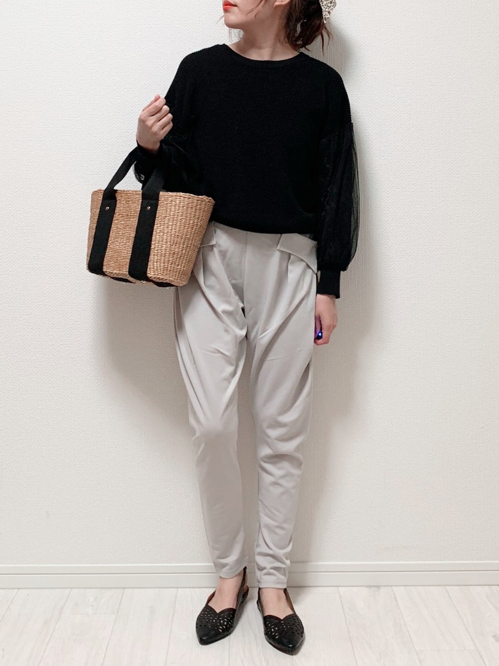 ブラック系のニット/セーター、グレー系のパンツ、ベージュ系のハンドバッグを着用したレディースの春コーディネートの1枚目の写真